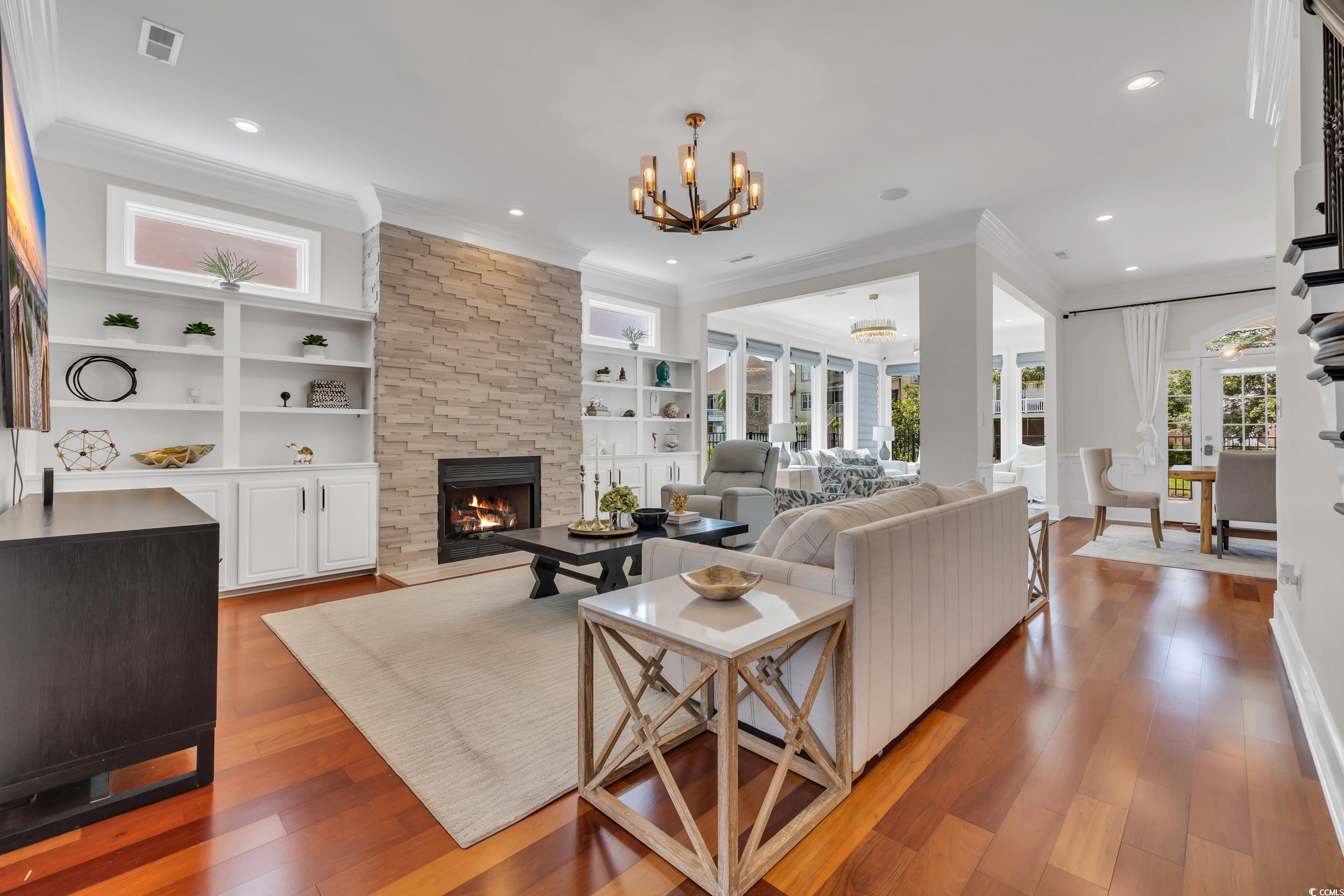 Living area with ornamental molding, a fireplace, a chandelier, wood-type flooring, and recessed lighting