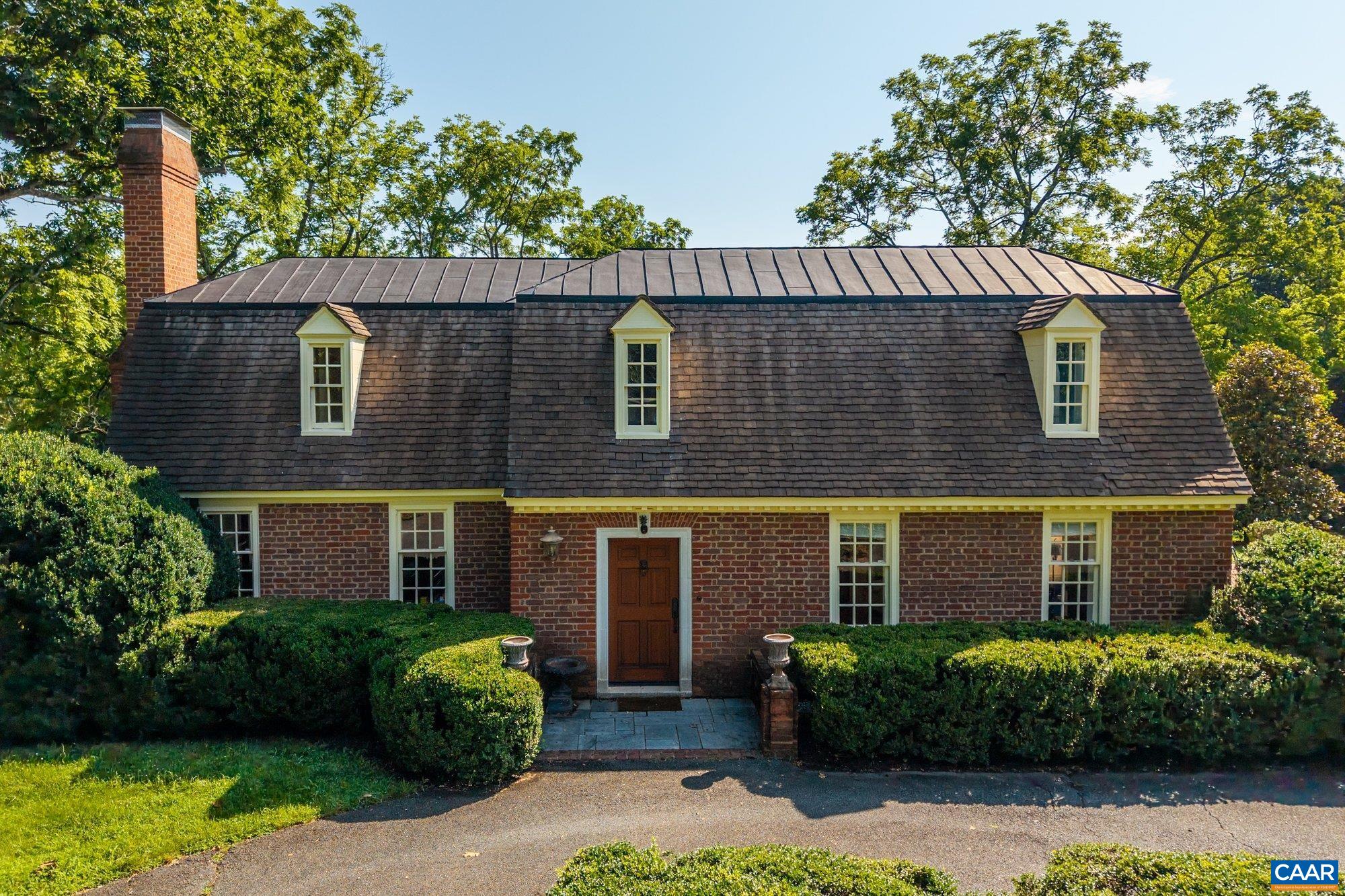 Tucked away on 11.5 peaceful acres, this French-style estate blends timeless European design with modern comforts. Originally built in 1964 using imported materials, the home has been thoughtfully renovated and expanded. It features 4 bedrooms, 3.5 baths, and a dramatic hallway with marble and wood inlay floors, custom built-ins, and a wall of windows. The spacious European-style kitchen includes a fireplace, window seat, and large island—ideal for everyday living and entertaining. A formal dining room and sunlit breakfast room add character and charm. Living and family rooms boast floor-to-ceiling windows framing pastoral and lake views. The fourth bedroom serves well as a guest suite or office with its own bath and entrance. Outdoor spaces include a covered porch, bluestone patio, and a pristine lap pool. A three-stall barn makes it equestrian-ready. Private yet close to town, this refined retreat offers serene living in a storybook setting.