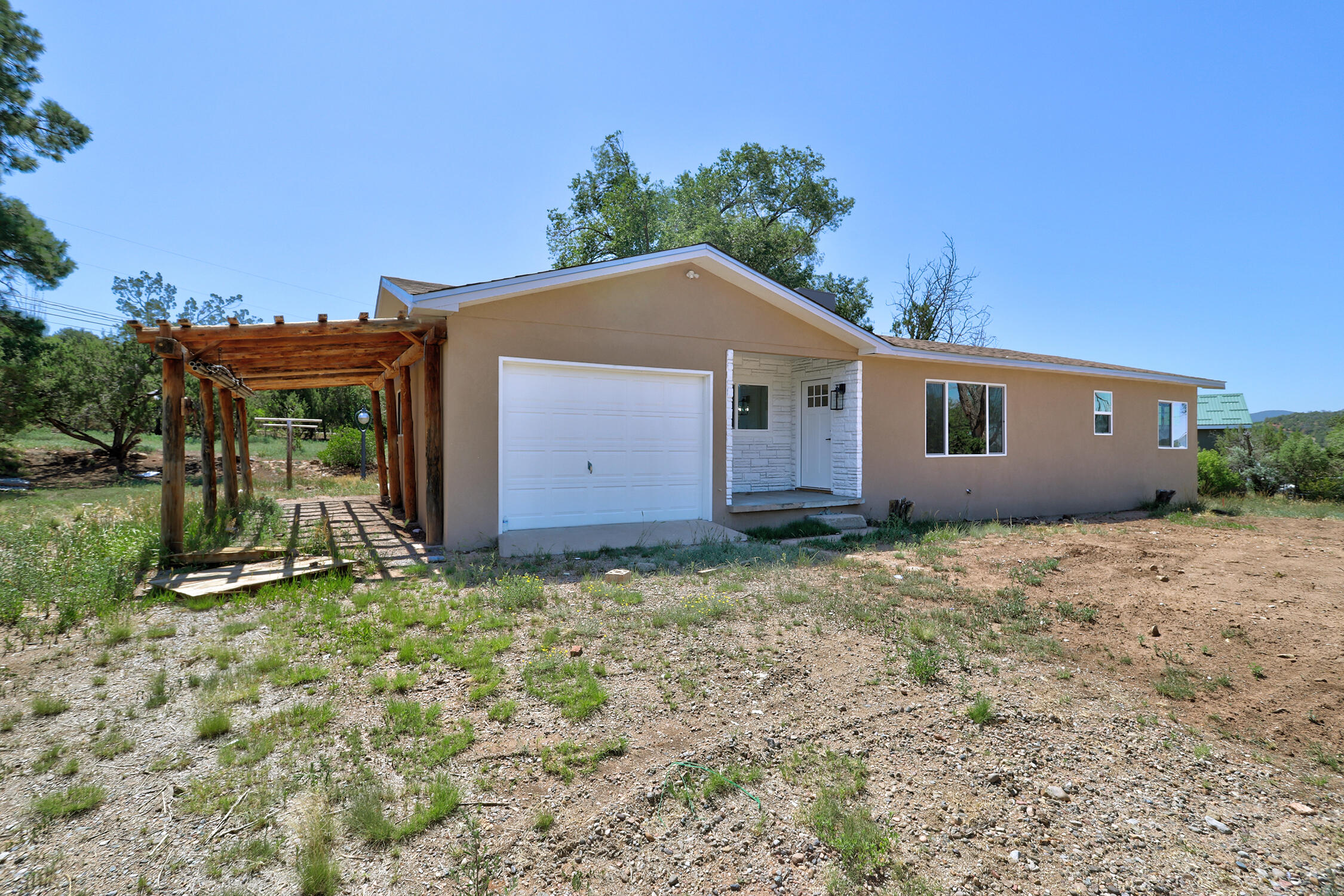 Country Living with Stunning Sandia Views! Step outside your front door and take in the breathtaking views! This updated 2-bedroom, 1-bath home sits on 1.14 acres and offers a new roof, water heater, furnace & refrigerated AC, plus an updated kitchen with new counters, cabinets, fixtures, and SS appliances. The bathroom has been upgraded with a new vanity, modern fixtures, a tiled shower, and a luxurious jetted tub. Enjoy year-round comfort in the spacious, finished, and heated sunroom--ideal for an office or 2nd living space. The home includes an attached 1-car garage that's perfect for a workshop area, a 1 car carport, plus a detached 1-car garage with additional workspace & storage. A 2nd outbuilding offers room for stalls and hay storage--great for animals, hobbies, or extra storage.