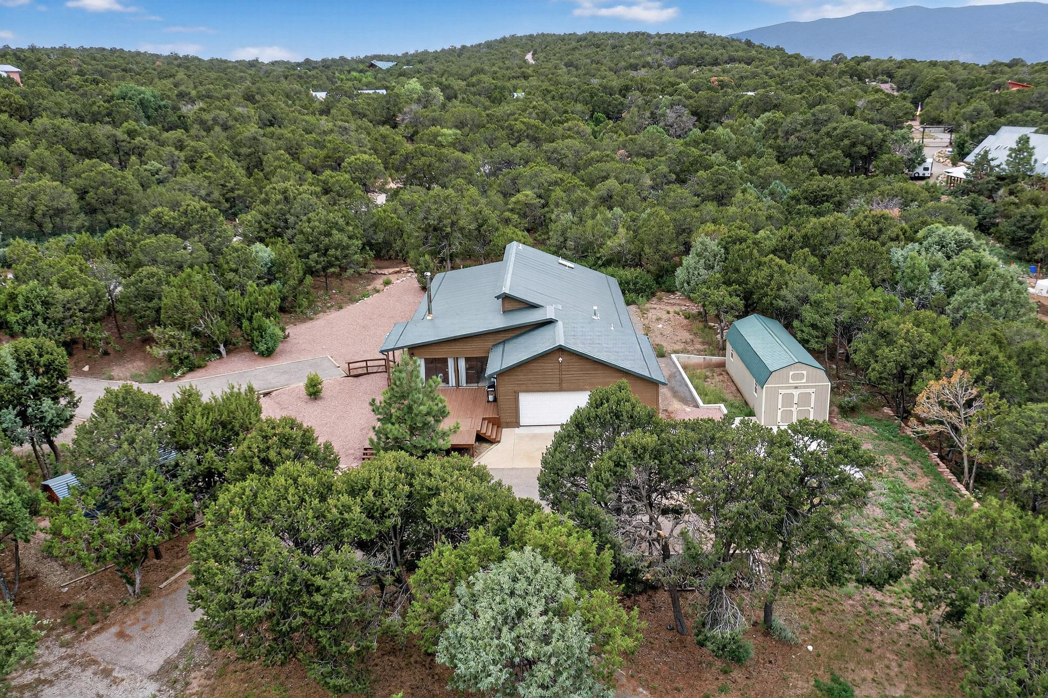 Mountain retreat on 2 wooded acres:  3-bedroom + bonus room. Community water, detached heated workshop and RV parking.  Fully fenced.  Enjoy the peace and privacy of gated living with the convenience of community water and easy I-40 access, just outside Albuquerque. This charming mountain property includes a large heated detached workshop, perfect for hobbyists, mechanics, or creatives -- plus an additional oversized storage shed for all your gear. Bring your RV! There's plenty of room for parking and toys, with space to spread out and breathe.Inside, you'll find a warm, inviting floor plan with flexible space for work or play, and all appliances convey, making this home truly move-in ready.