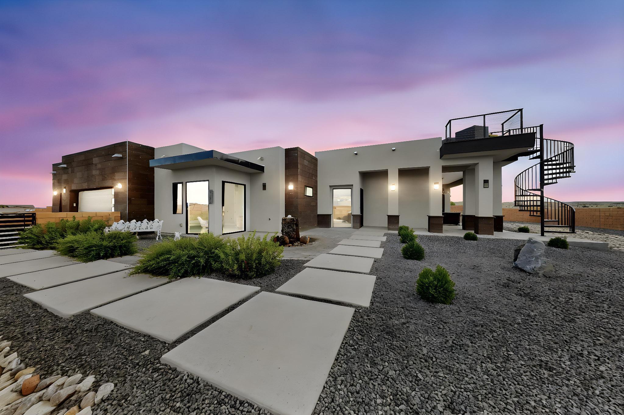 Experience breathtaking Sandia Mountain views from this showstopping custom home in Petroglyph Estates, designed by Eric Spurlock. From the striking 14' ceilings to the expansive picture windows and designer chandeliers, every detail exudes luxury. Enjoy dual patios, a custom upstairs view deck with fire features, and a built-in BBQ--perfect for entertaining. The chef's galley kitchen boasts black stainless appliances, waterfall granite island, and custom cabinets. Unwind in the spa-like primary suite with soaking tub, walk-in shower, and dual walk-in closets. RV pad, 3-car garage, wood-burning outdoor fireplace, and more--this home is pure perfection.