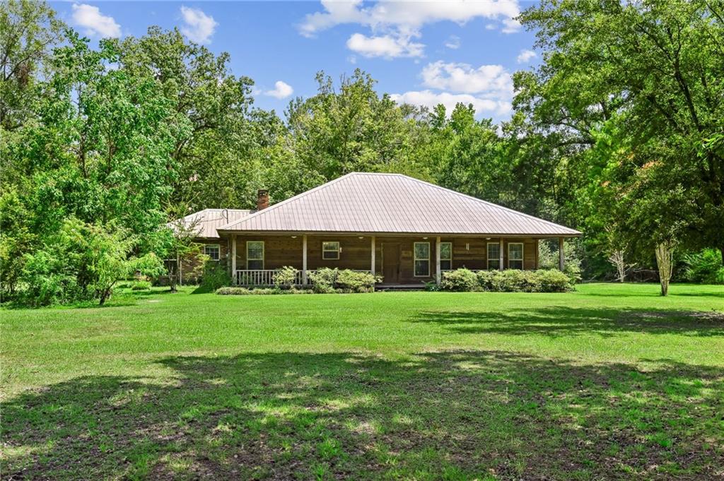 This delightful residence is situated on a lush 1.5 acres on the outskirts of town, offering a perfect blend of charm and tranquility.  The inviting living room/den boasts a wood-burning fireplace, vaulted ceilings, and double doors that lead to the rear deck.  With three bedrooms and two full bathrooms, there is ample space for comfortable living.  An additional bonus room upstairs provides versatile options for a study, craft area, guest accommodations, or playroom.  The kitchen features an open layout, complemented by a conveniently located laundry room accessible from the garage.  The expansive yard offers plenty of room for outdoor activities, gardening, parking your RV/boat, or simply soaking in the peaceful ambiance from the front porch or rear deck, whether on a serene morning or a quiet evening.  The property is adorned with a durable metal roof and gorgeous trees, enhancing its appeal. Countless cherished memories have already been created in this charming home, with many more awaiting.  We invite you to come and see for yourself!