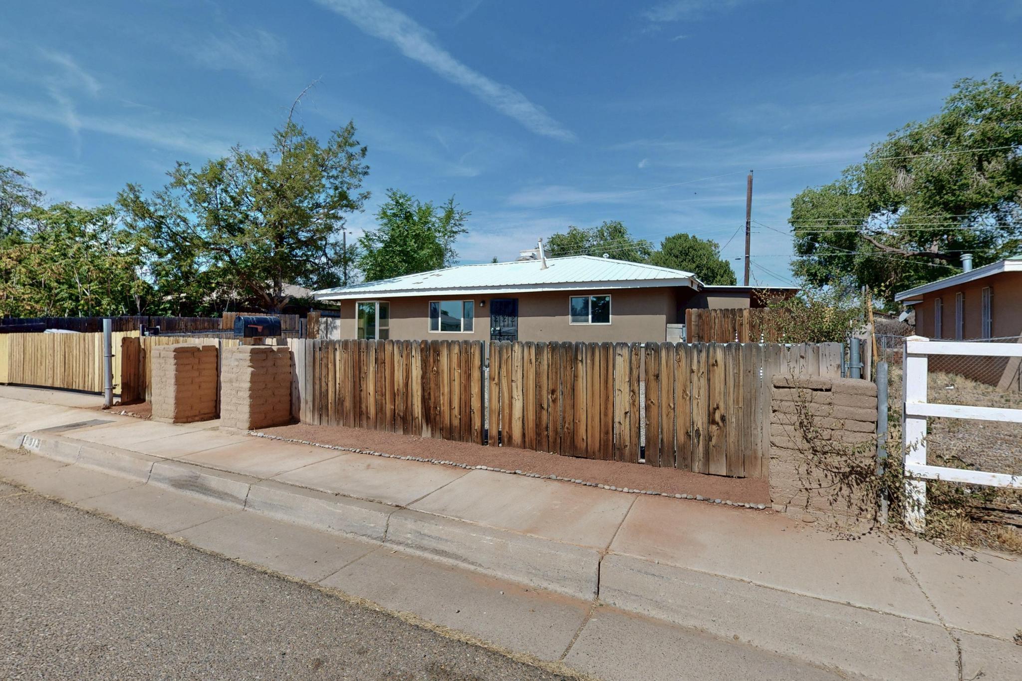 Must-see! Lovely recently renovated 3 bedrooms,  2 bathrooms home in the North Valley. Cozy family room with adobe walls leads to the inviting covered back yard area with outdoor fireplace, carved vigas & landscape planters-seating, perfect for the family gatherings! Ample exterior back and front yard. The recent updates include; remodeled bathrooms, walls & flooring, evaporative cooler, tankless water heater, baseboard heaters. The stucco, electrical panel and windows were redone within the last few years. The convenient centralized location is a plus!