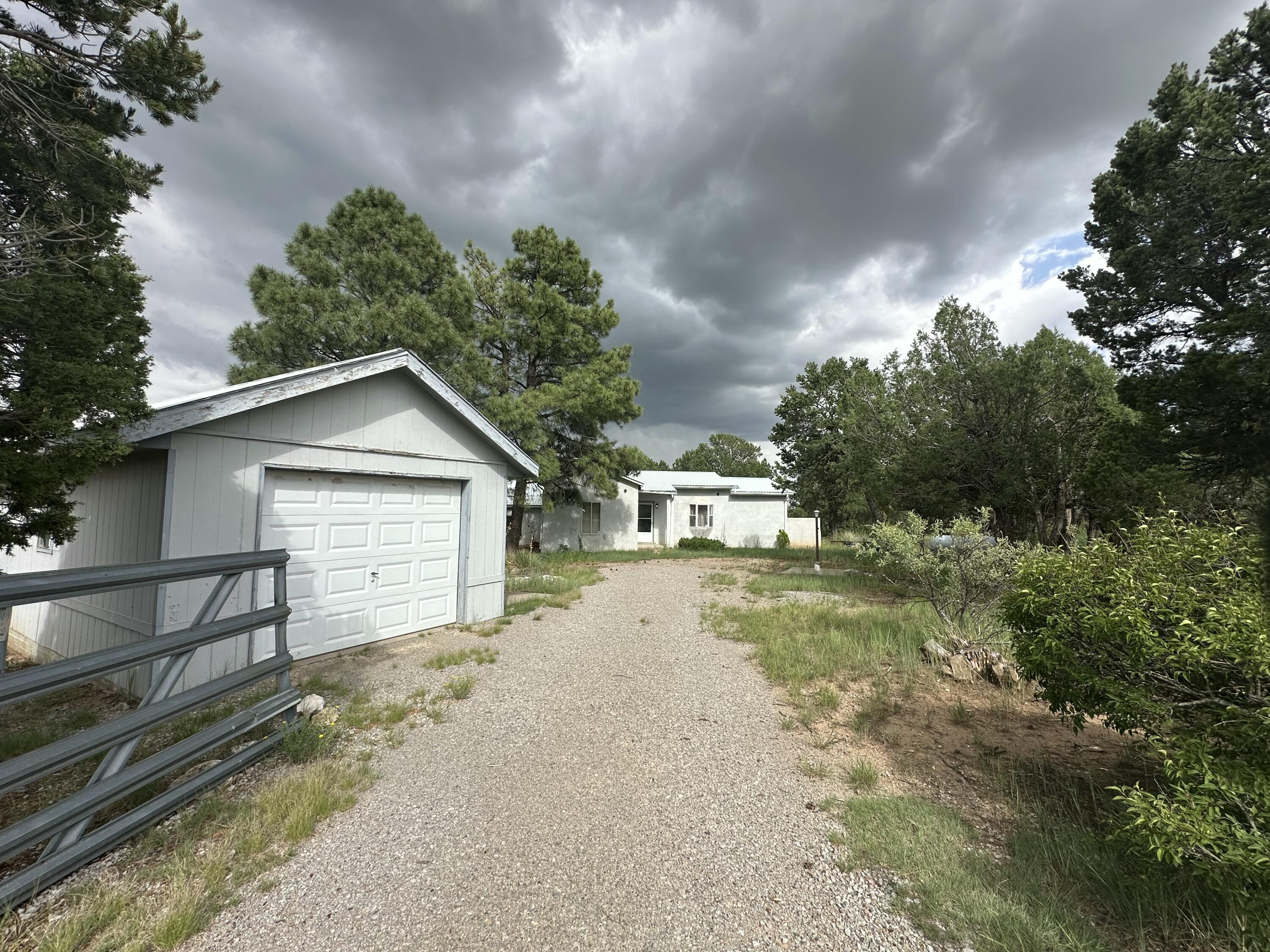 Nestled among tall pines on over 2 acres, this Tijeras retreat offers fresh mountain air and endless potential. Featuring a durable metal pro panel roof and a detached single-car garage, this home is perfect for buyers ready to add their personal touch. With a little TLC, this charming property could truly shine. Enjoy privacy, space, and the beauty of nature--just a short drive from the city!