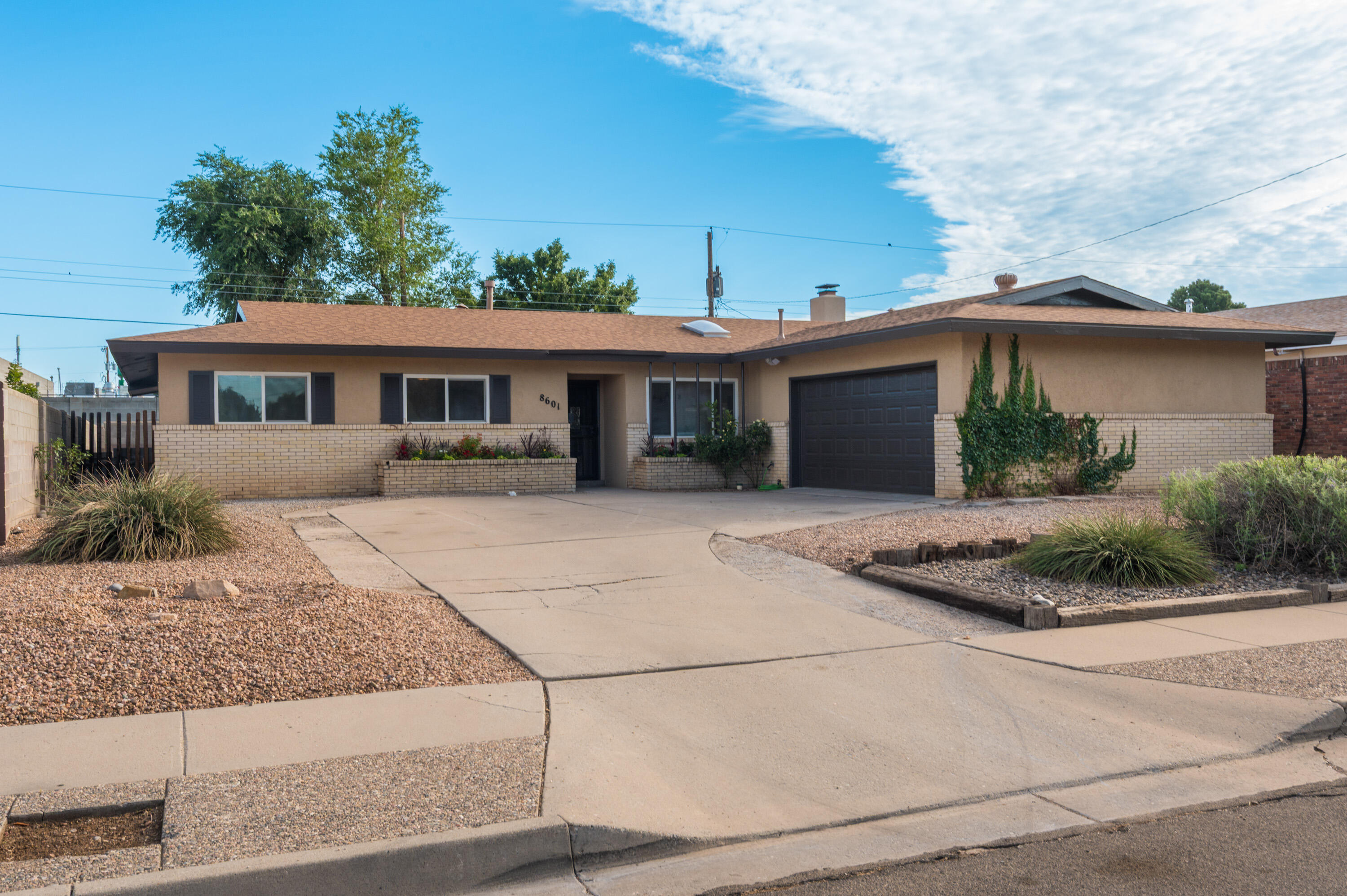 Step into this well-loved home  in Albuquerque's Northeast Heights. With 3 bedrooms and 1.5 baths spread across almost 2,000 sqft, the home features abundant natural light, a welcoming fireplace in the open living room, and a flexible sunroom/den layout. The kitchen is ready to support your cooking needs with modern appliances and a bar top area for entertaining.. Outside, enjoy a generously sized lot with a two-car garage, a covered patio, and mature landscaping. Located just minutes from schools, parks, and uptown shopping, this home offers timeless charm and unbeatable convenience.
