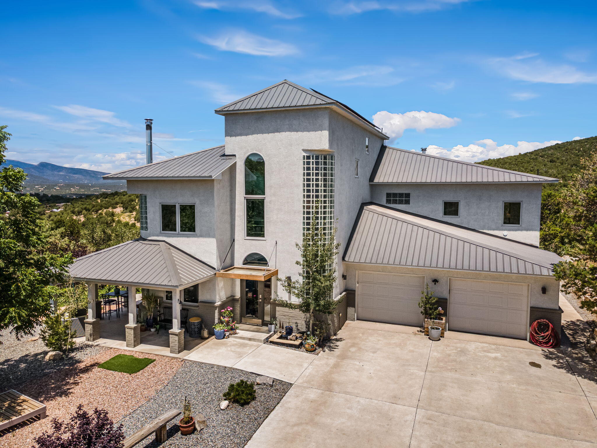 You have never seen a property like this in the east mountains. This is a gorgeous home sitting on 4.68 acres (2 lots). As you approach you will see how it majestically rises through the trees. Friends lovingly call it ''the castle''. Surrounded by Pinon & Juniper. Sit on the zen chair and listen to the birds all day and the owl that nests nearby at sunset. Watch the raptors riding thermals right above the house. Raise your own chickens & goats with a coop & goat pen on the property.  When you walk in the front door, you are taken by the high ceilings with exposed beams. The home feels both modern, but also connected to nature. With large windows throughout, who needs artwork on the walls. The views are stunning! The three guest bedrooms and full bath downstairs give separation between