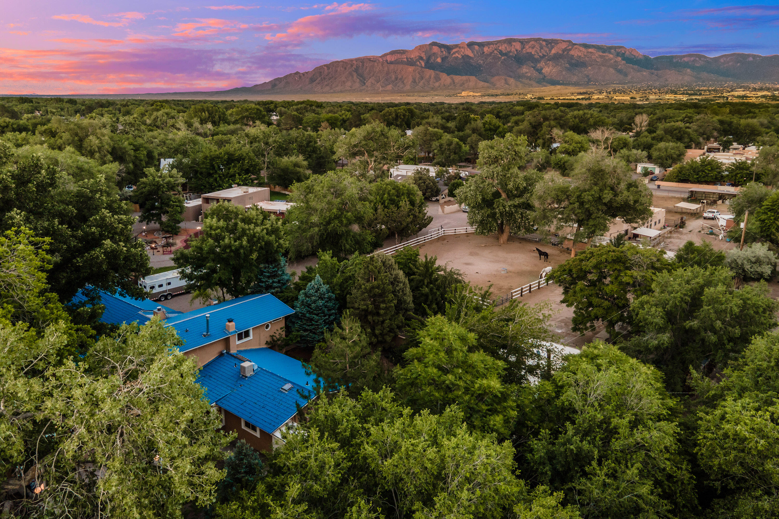 Nestled on a serene 1.6 acre gated lot in the sought-after Far North Valley, this lovely Northern New Mexico-style horse property offers privacy, charm and views in the heart of the city just minutes from the Bosque open space trails, dining, and shopping. The property also boasts a two bedroom guest house (ADU) that is perfect for extended family, in laws or additional rental income.  This expansive home is designed for both relaxation and entertainment.  The home opens up to the park-like backyard that overlooks a charming vintage barn with 3 stalls, a tack room, and a paddock. A welcoming courtyard invites you to the main house, where you'll find a perfect blend of rustic charm and modern amenities. The generous owner's suite is a true retreat, featuring 3 walk-in closets.