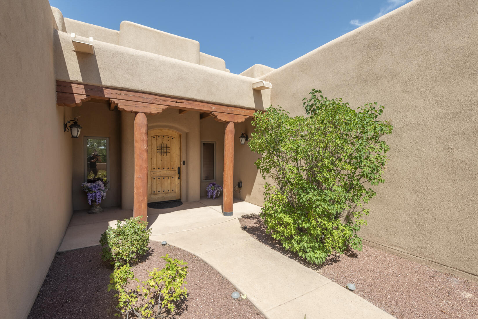 Enter via the treelined drive to a gated Estate in Tierra de Corrales. This custom pueblo style home radiates elegance and comfort. The exclusive spacious owner's wing showcases a private bathroom resembling a spa, featuring dual vanities, a jetted garden tub, and a luxurious walk-in shower, gas log fireplace and stunning views making it a perfect sanctuary. The living room is defined by its lofty wooden ceilings, decorative beams, and a cozy kiva fireplace that creates a warm ambiance. The gourmet kitchen is a chef's paradise, complete with granite surfaces, a travertine backsplash, knotty alder cabinetry, premium appliances, an expansive island, and a butler's pantry. Additional amenities feature Owned Solar Panels, numerous rooms throughout the house for a myriad of lifestyle options,