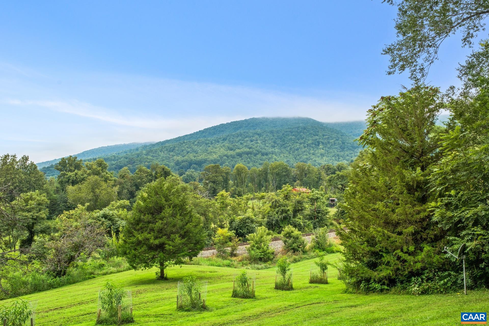 Welcome to Mountain Magic, a serene cottage retreat nestled on two private acres in the heart of Crozet, Va. Surrounded by breathtaking mountain views and mature trees, this home offers the perfect blend of cozy comfort and peaceful seclusion—just 2 miles from downtown Crozet. Step onto the inviting front porch and soak in the natural beauty that surrounds you—perfect for morning coffee or sunset evenings. Inside, the open-concept kitchen, dining, and living areas create a warm, connected space ideal for both entertaining and everyday living. Multiple cozy nooks offer the perfect spots for reading, visiting with friends, or enjoying quiet moments alone. The spacious primary bedroom includes an en-suite bath. Downstairs, the walkout basement provides flexible bonus space ideal as a guest suite, additional living area, or family room. Outside, you'll find a well-maintained yard that's perfect for entertaining, along with a garden shed and additional storage/workshop area—a great setup for hobbyists, gardeners, or anyone needing extra space. Minutes to Chiles Orchard, local restaurants, and charming downtown Crozet. Don’t miss this rare opportunity. Located in the sought-after Western Albemarle School District