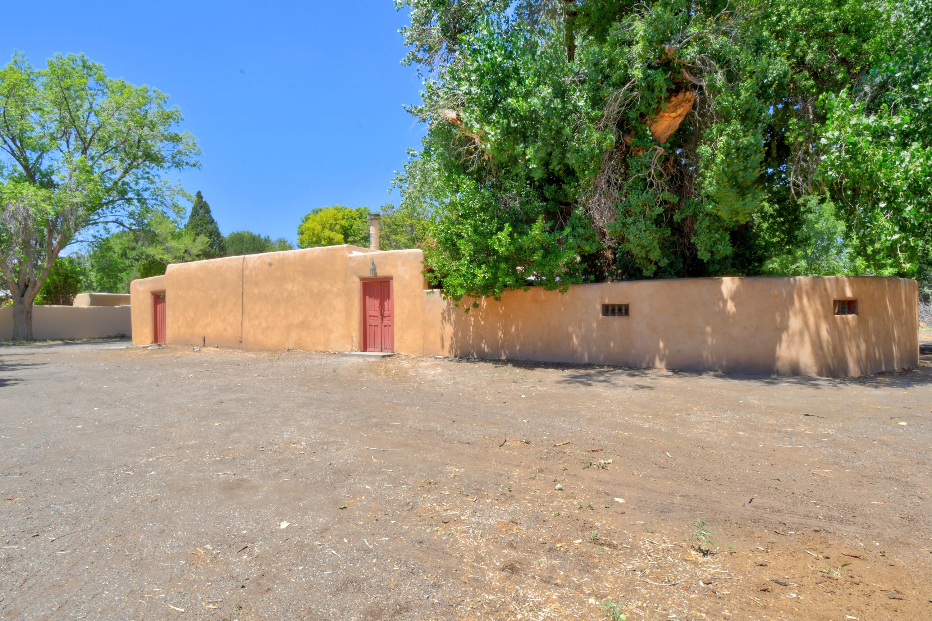 Fantastic Los Ranchos location on west side of Rio Grande Boulevard on a dead end street.. Rustic SW style home needs a little TLC. Brick floors throughout except for sunroom has saltillo tile floors and a  ceramic tile entry foyer.Skylights are throughout, three firelaces, living room has beam & T&G ceilings. Each bedroom has separate entrance to outside. Primary bedroom has door to courtyard, other two bedrooms have doors to portal. Two bedrooms share Jack & Jill bathroom. There is a covered patio in back. Two bedroom guesthouse is over 1,000 square feet and is just steps from the main house and has a wood burning stove. Electric baseboard heat. Detached two car garage.