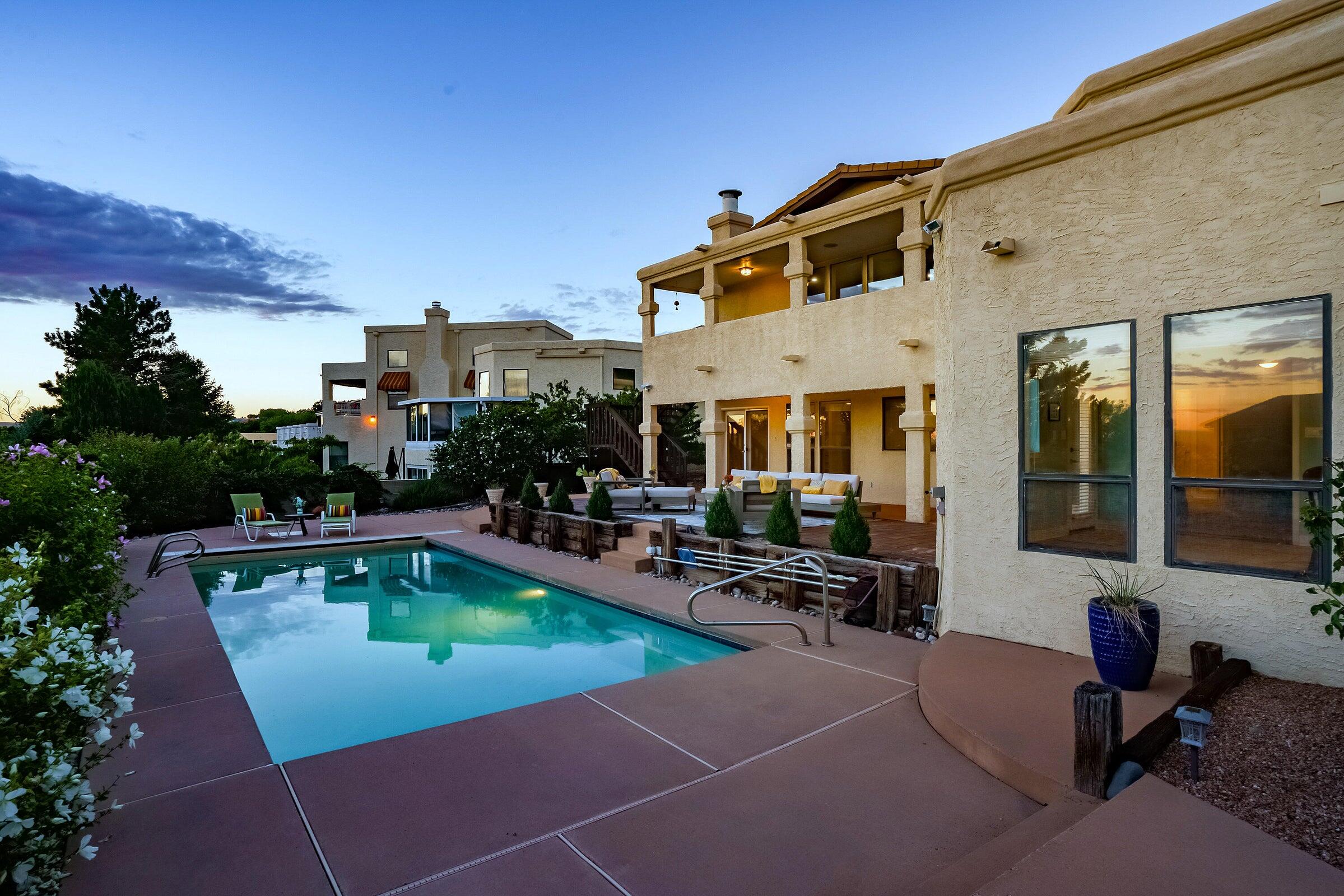 Beautifully updated home in the foothills with stunning views and high-end finishes throughout! Featuring 2 primary suites, 3 living areas, and over 3,700 sq ft, this home is ideal for multi-gen living or those who love to entertain. The all-new gourmet kitchen boasts quartz counters, custom cabinets, butler's pantry, wine/coffee bar, and luxury fixtures. The redesigned primary bath includes a soaking tub, Carrara marble, and CA-style walk-in closet. New flooring, fresh paint, and a marble-accented fireplace elevate the style. Enjoy a heated pool with new pump & auto cover, refrigerated air (2021), and breathtaking sunsets from the balcony. Near trails and the beauty of the Sandia foothills!