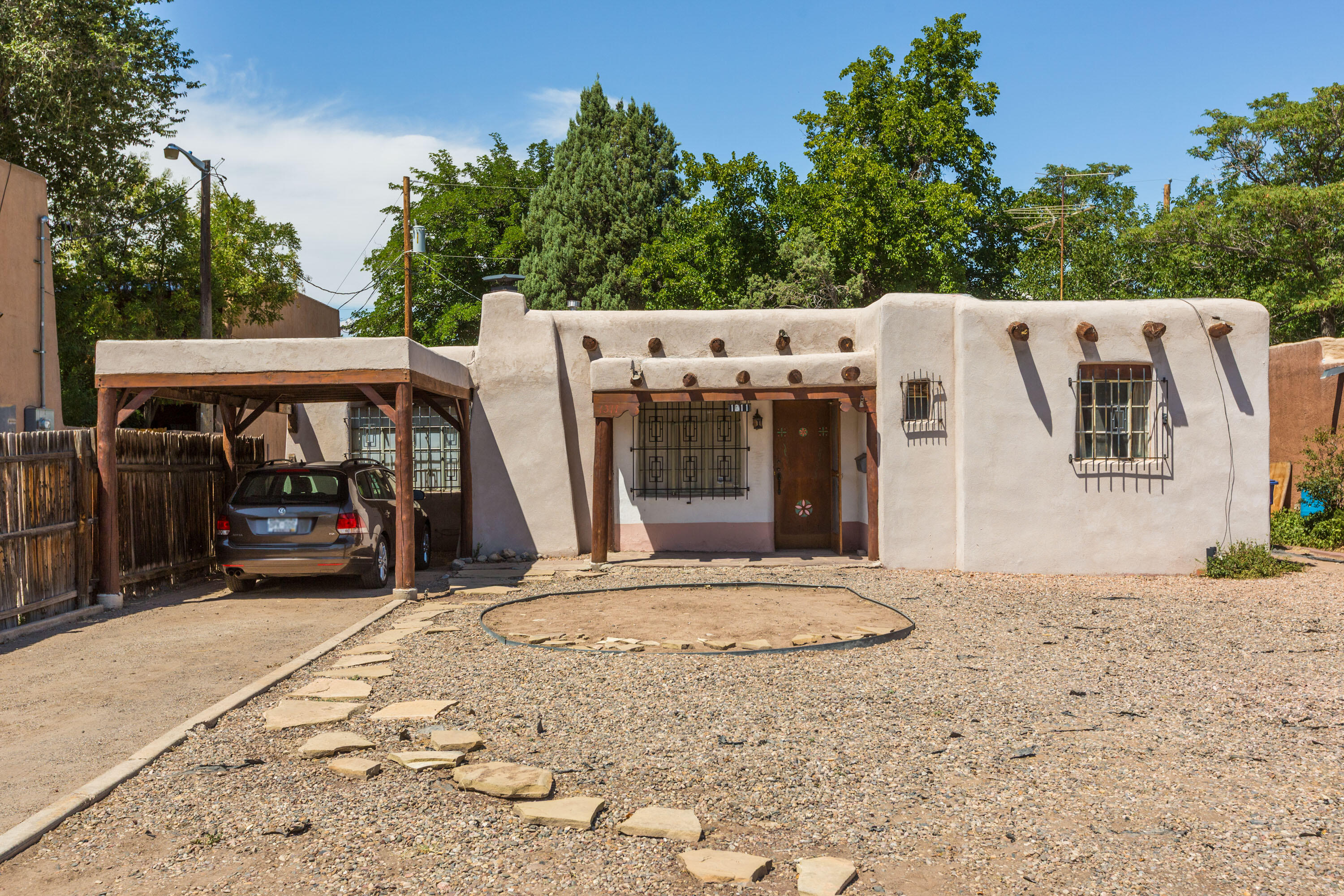 LOCATION! LOCATION! LOCATION!  Near Alb CC, Alb Bio Park & Botanic Gardens, Old Town & Sawmill District w/arts, cultural, dining, UNM & Nob Hill, Downtown!  Old world charm 3BDR/2BA pueblo home w/wood beam ceilings, vigas, carved corbel doorway & cozy wood fireplace. 2 spacious living areas w/picture windows & lots of natural light.  Cute kitchen connects to a butler pantry w/cabinets.  Primary bdr has a separate office overlooking the backyard w/private patio access.  One bdr features a brick floor & large walk-in closet. Two updated baths. Ample storage thru out. Beautiful backyard w/shade tree & open brick patio & covered patio for family gatherings & entertaining outdoors.  2 large sheds & workshop space.  Appreciate 1940s nostalgia, uniqueness & character and add your own updates!