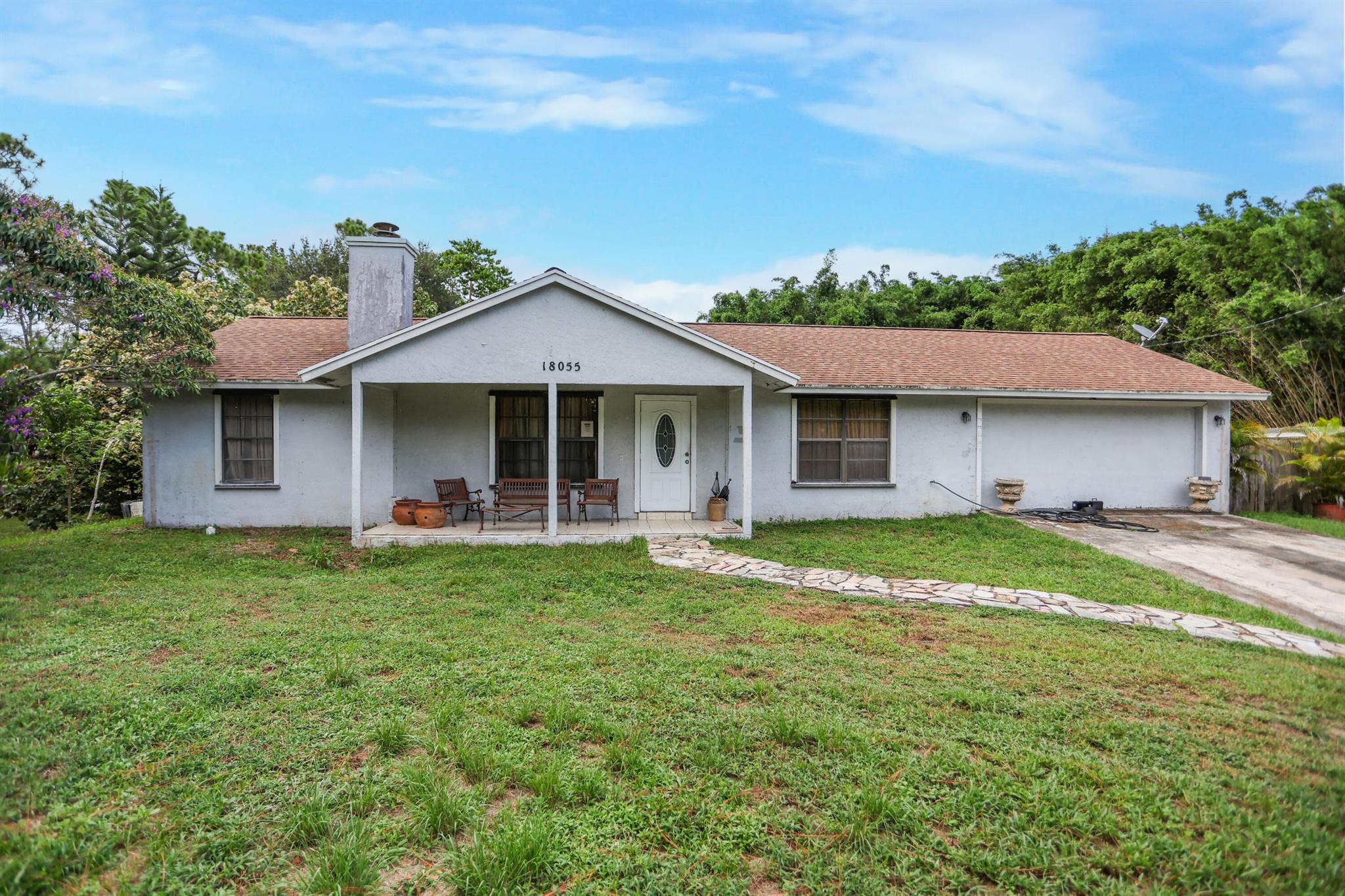 Welcome to 18055 W Sycamore Dr in beautiful Loxahatchee, just minutes from the growing community of Westlake! This charming 3-bedroom, 2-bathroom home offers over an acre of land, providing the perfect canvas for your dream home. Updated roof in 2020.  Inside, you'll find a spacious layout full of possibilities, with generously sized bedrooms, a split floor plan, and ample natural light throughout. While the home is in need of updating, it presents a rare opportunity for customization and value-add improvements--ideal for investors, renovators, or anyone looking to create a personalized retreat in a peaceful, no-HOA neighborhood. Enjoy the freedom of country living with plenty of room to expand, build a guest house, or even add a pool. With its prime location near shopping, dining, and top-rated schools in Westlake, this property offers the best of both space and convenience. Bring your vision and make this home your own!