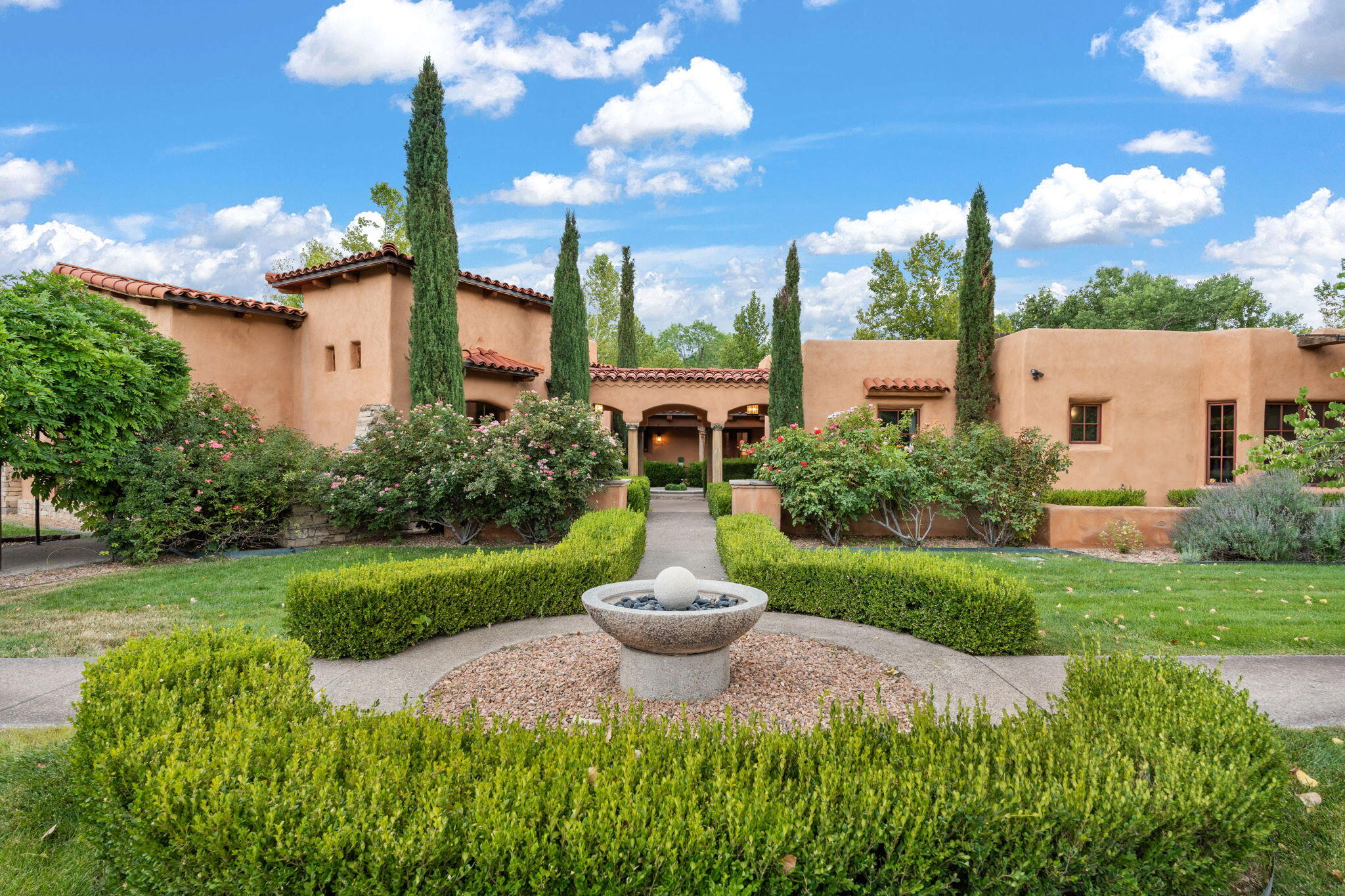 Gorgeous, peaceful, remarkable.  A beautiful mediterranean adobe villa by John Calvin.  Set in a lush and well-manicured setting on a very special street in the Village of Los Ranchos. Walk or ride your bike to Los Poblanos Historic Inn, Campo, Los Ranchos Growers Market, and much more.  The home features a chef's kitchen, spacious en-suite bedrooms, stunning garden views from every window, and a large koi pond and a private irrigation well..  Radiant heat, central AC, Wolf range, 5 fireplaces including an outdoor kiva, travertine floors, 3 Car garage.  Separated & Quiet Master Suite . Kitchen features include: Wolf range, subzero fridge, double-oven, wine cooler, & oversized island. Enjoy views of the gardens and landscaping from every room, with a walled backyard.