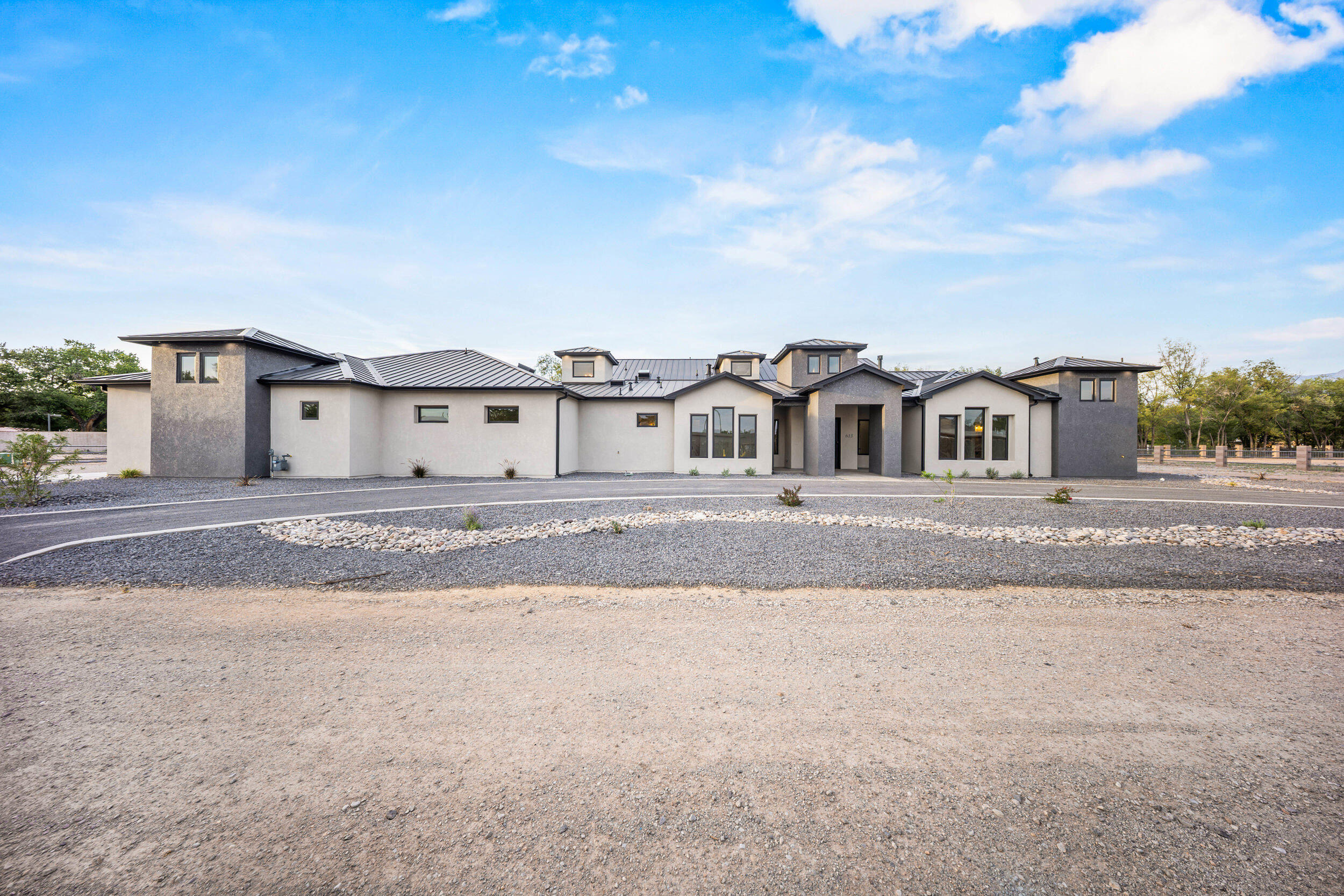 Contemporary Luxury home on 1 acre. Location, location, location! This stunning home sits in the heart of the North Valley within a private gated community. Offering 3968 sq ft & 6348 sq ft under roof & features 4 bedrooms (each with a walk-in closet), office, bonus/theater room and oversized finished 4 car garage. Inside enjoy 14' ceilings with natural wood beams & a grand entry tower. The chef's kitchen boasts quartz slab counters, custom cabinets, commercial grade appliances, wine cooler & a butler's pantry w/beverage fridge. Outdoors take in mountain views while enjoying the built-in kitchen & cozy fireplace. This lot offers direct backyard access to walking & biking trails. Blending luxury living with NM's natural beauty. A rare find combining style, comfort & unbeatable location!