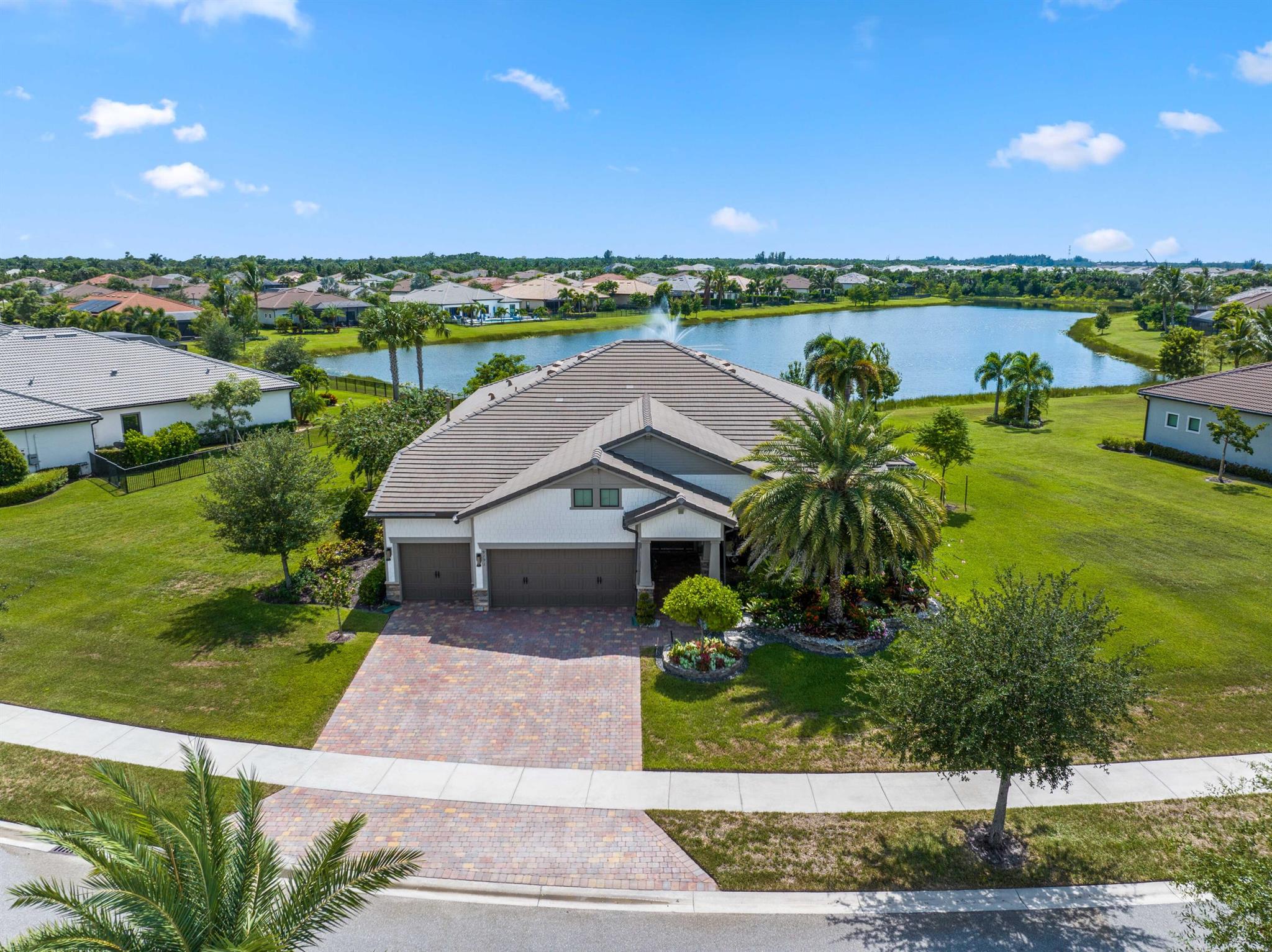 On one of the largest lots in Ancient Tree, this half-acre lakefront home offers wide fountain views and a backyard built for enjoyment. The saltwater heated pool, 6 1/2 feet deep, with fire bowls, hot tub, and panoramic screen enclosure, creates the perfect outdoor retreat. Entertain with ease on the patio featuring a summer kitchen with grill, fridge, ice machine, and trash. Inside, the custom kitchen includes 42'' upper cabinets, upgraded quartz, built-in pet bowls, and premium appliances: Fulgor range with gas burners and double electric ovens, wall oven, microwave, and pot filler. The open great room has coffered ceilings, while the primary suite offers generous closet space. Natural gas serves the dryer, water heater, grill, and burners. Oversized 3-car garage plus golf cart space.