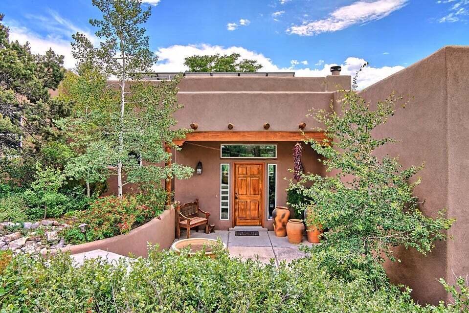 Santa-Fe style home in Magic Valley - thoughtfully planned & designed to capture breathtaking Sandia Mountain vistas.  This split-level design hugs the lay of the land & offers amenities galore w/4 private outdoor living spaces; extensive gardens w/colorful flowers & shrubs plus your own quaint potting shed. Large windows, amazing light; chef's kitchen; spacious sun-filled living area w/custom corner fireplace, raised tongue & groove wood ceiling w/beams. 2205 sf detached workshop & studio is a perfect setting for a home-based business, telecommuting via high-speed internet or haven for creative pursuits.  SOLAR SYSTEM OWNED! Experience nature...peace of mind & serenity. Floorplan included in docs of house & studio/shop layout. New TPO roof on house in process. Gate code in showing time.