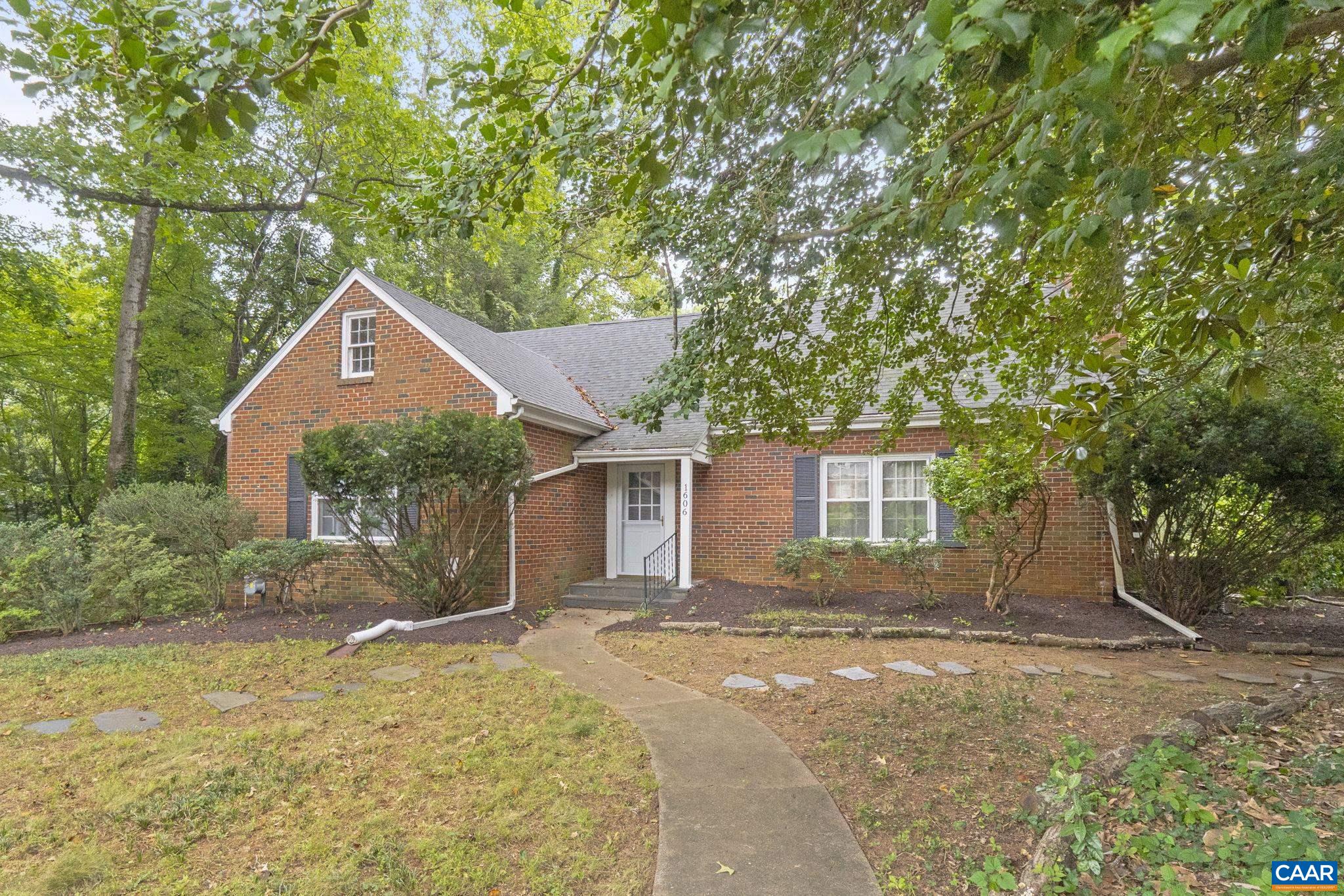 Charming and solidly built 1950s brick home on a spacious 0.5-acre lot in a prime Charlottesville location. Hardwood floors run throughout the main level and continue into a thoughtfully designed half-story addition featuring a modern primary suite with walk-in closet and a spacious en suite bath—complete with soaking tub, dual vanities, and tiled shower. The main level includes three additional bedrooms, one of which was the original primary with its own attached bath. The living room offers a decorative fireplace ready for a gas insert framed by custom built-ins and the kitchen has new porcelain tile and walks out to a side porch. The finished basement features a wood-burning fireplace, full height windows, and new LVP flooring, adding flexibility for recreation or work-from-home space. Recent updates include roof (2021), HVAC coil (2020), tankless gas water heater (2012), garage/basement windows (2012). LEAP Certified