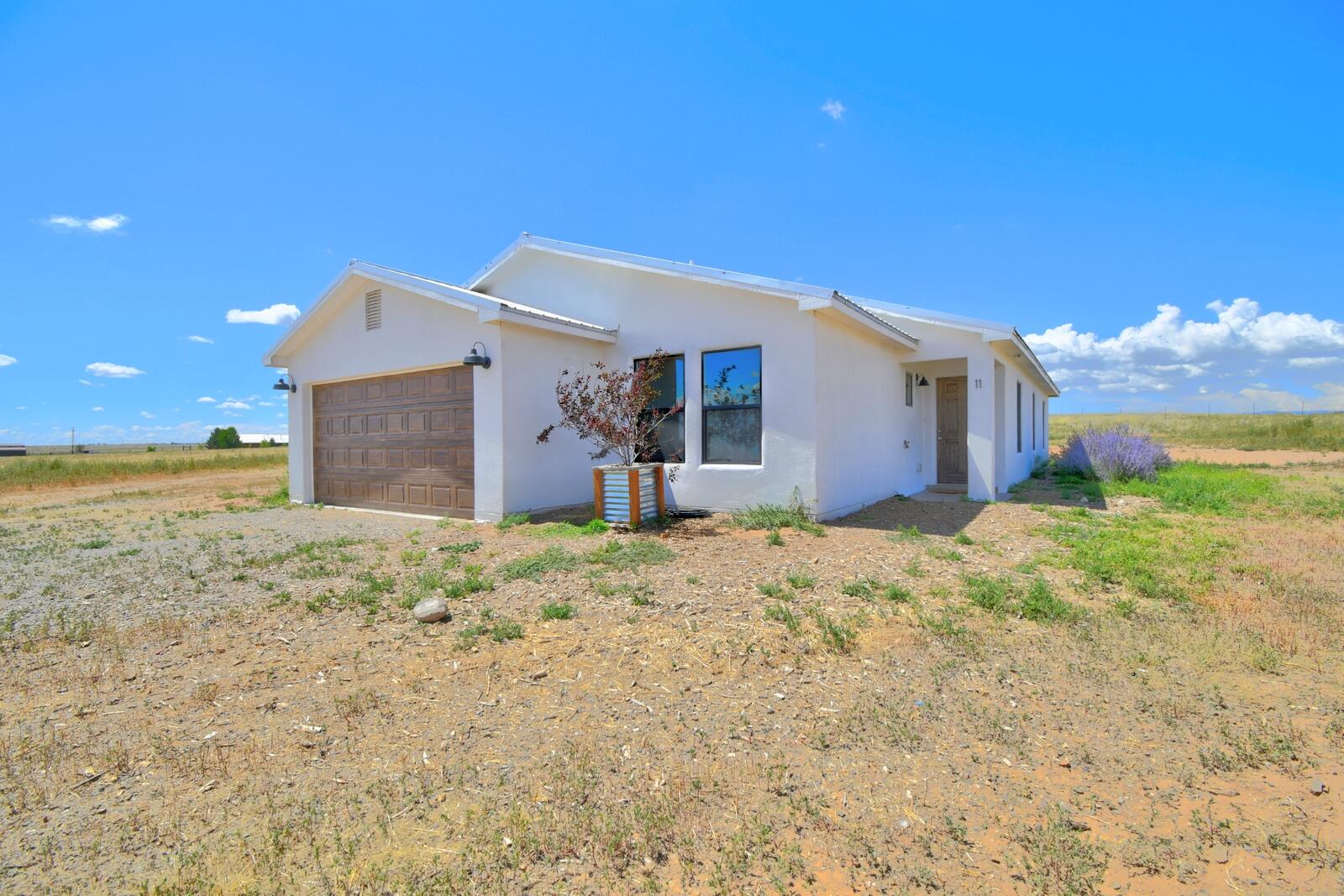 Enjoy country living with modern comforts in this 2017-built home, set on nearly 14 acres with its own private well and natural gas. The inviting 4-bedroom, 2-bath layout blends rustic charm with contemporary style and captures stunning views of the Pecos, Sandias, and South Mountain. Inside, you'll find an open concept design with abundant natural light, stainless steel appliances, a farmhouse sink, subway tile accents, wood-look tile flooring, custom built-ins, new carpet, and a durable metal roof. Just minutes from I-40, shopping, and schools--this is a must-see property where comfort and scenery come together beautifully.