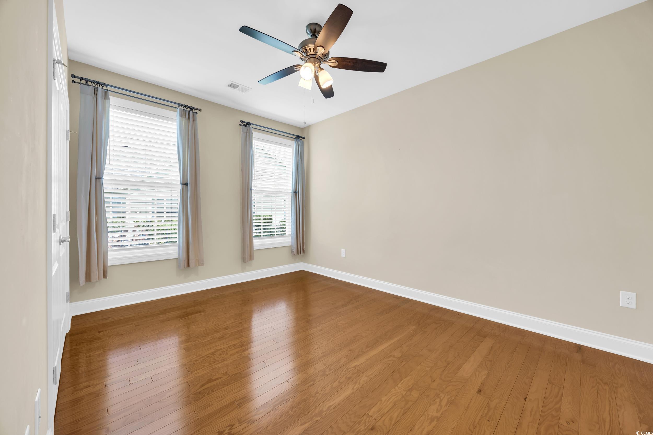 Empty room featuring hardwood / wood-style flooring and a ceiling fan