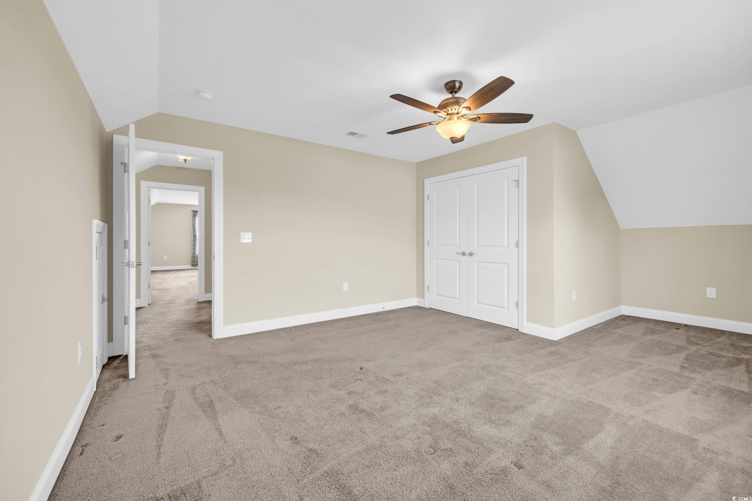 Additional living space featuring lofted ceiling, light carpet, and ceiling fan