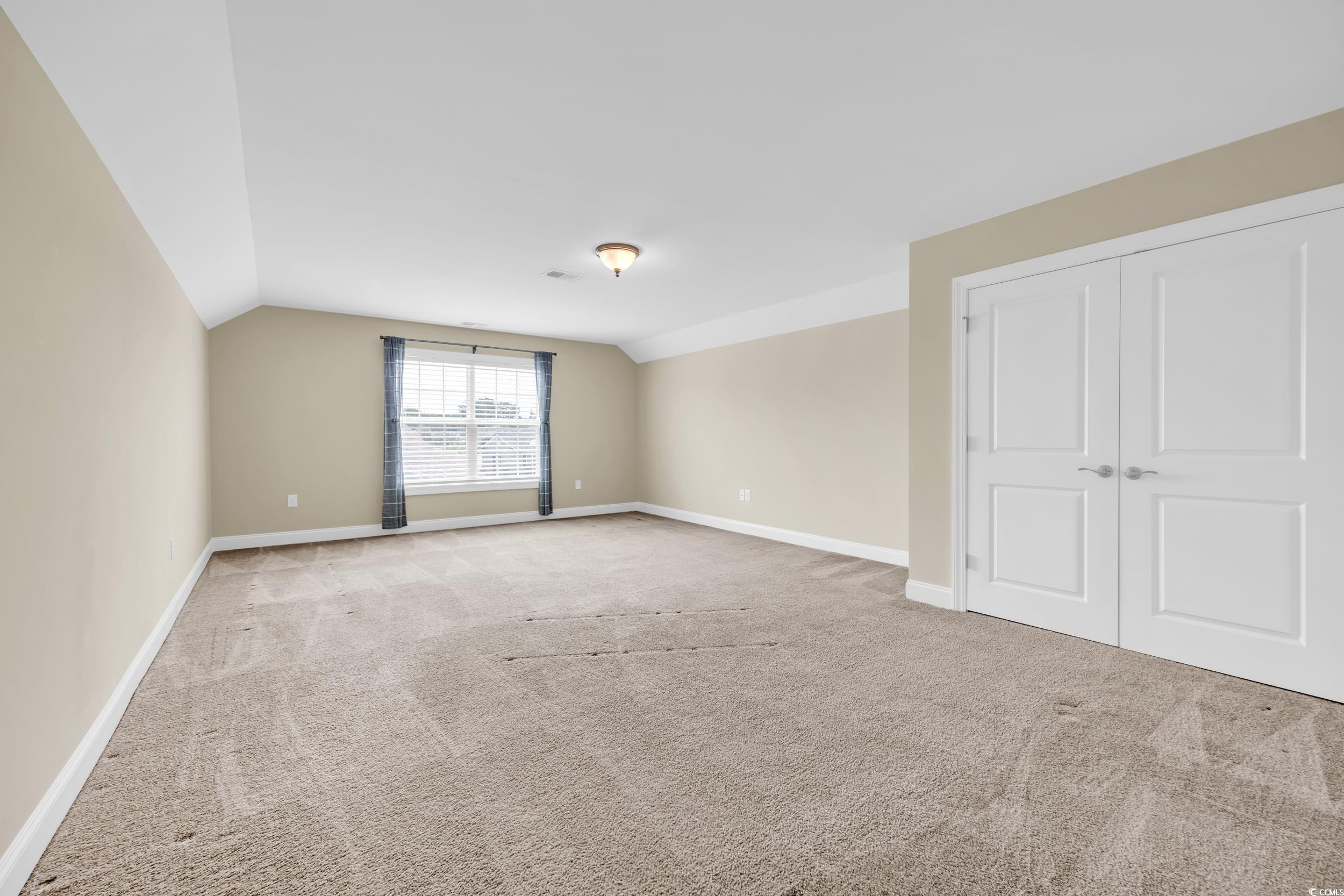 Unfurnished bedroom with lofted ceiling, light carpet, and a closet
