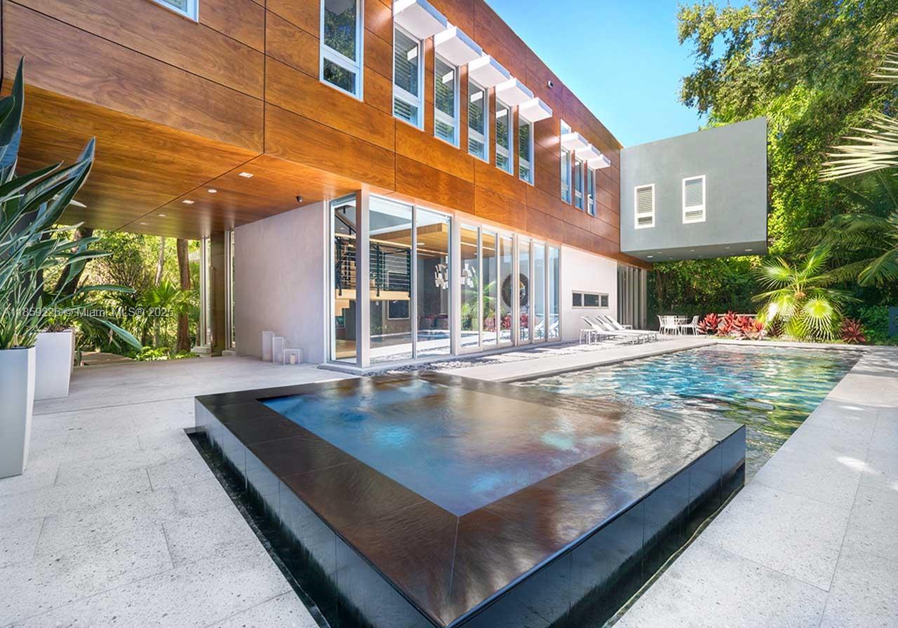 Hammock House, a spectacular tropical modern-style home in the gated & historic bayfront community of Camp Biscayne. A state-of-the-art residence w/walls of glass that create a seamless blending of interior & exterior spaces. The home offers the ultimate in privacy & is surrounded by lush tropical landscaping amid a forest of mature oak & mahogany trees. The main house features a stunning Boffi kitchen, a large modern office, staff quarters + 4 ensuite BR’s, including a lavish master suite w/spa-like bathroom featuring a glass-enclosed rain shower, soaking tub & sauna. Additional notable features include a 1/1 guest house and a serene outdoor oasis w/ heated pool, Jacuzzi & summer kitchen. Just steps from the Grove village’s galleries, boutiques, cafes and bayfront parks & marinas.