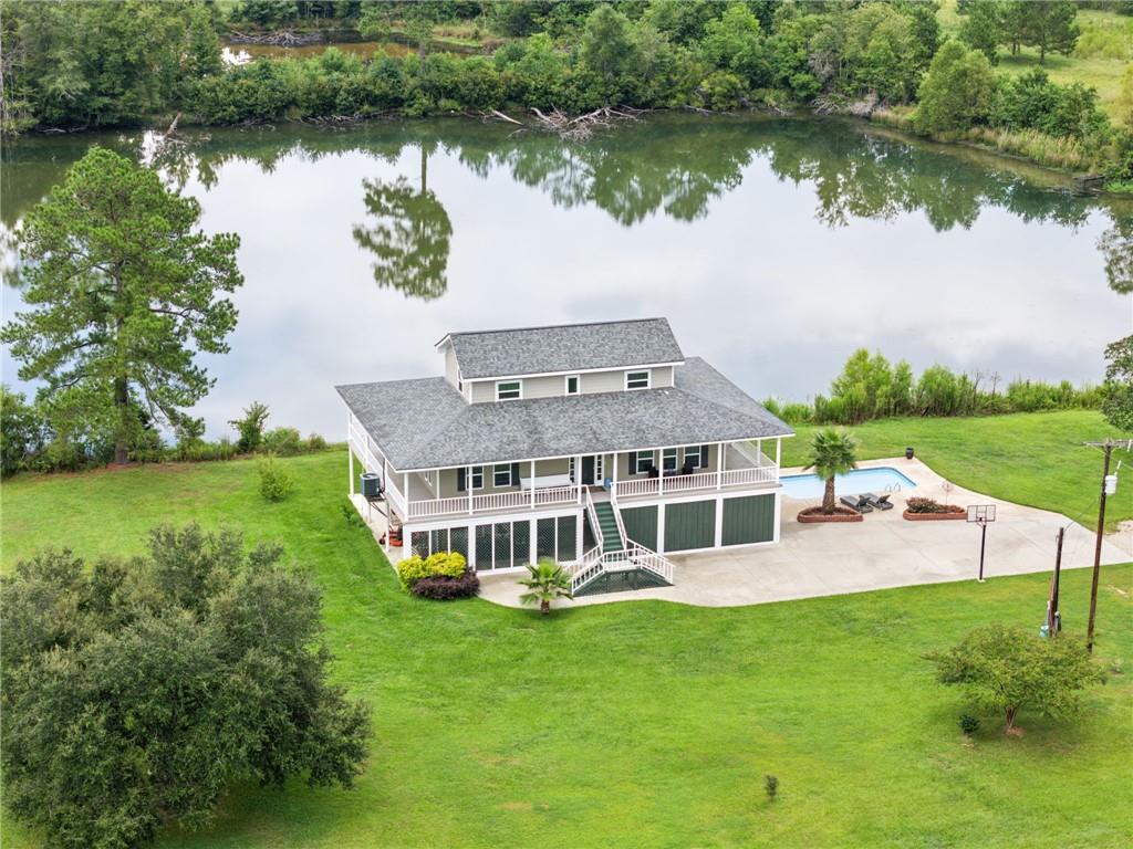 This stunning 22.74 acre 4 bed 4 bath Acadian offers the perfect blend of charm, comfort, and wide-open living. From the moment you step onto the glorious wrap-around porch, you’ll be drawn to the peaceful views of open pastures, two stocked ponds and beautiful mature trees. Inside, you’ll find a beautifully renovated home with thoughtful details throughout, including triple crown molding, a spacious layout with bedrooms both up and down, and a recently finished out flexible downstairs space that can serve as a man cave, office, party room, or private apartment. Outdoors is where this property truly shines—whether you’re fishing in the bass-stocked pond, cooling off in the in-ground pool, or tending to horses and livestock with the 4-stall stable (converted to a shed). With endless possibilities, this property is more than a home—it’s a private Southern paradise waiting to be yours. (Square footage includes the 918 sq ft apartment/office with full bath on ground floor)