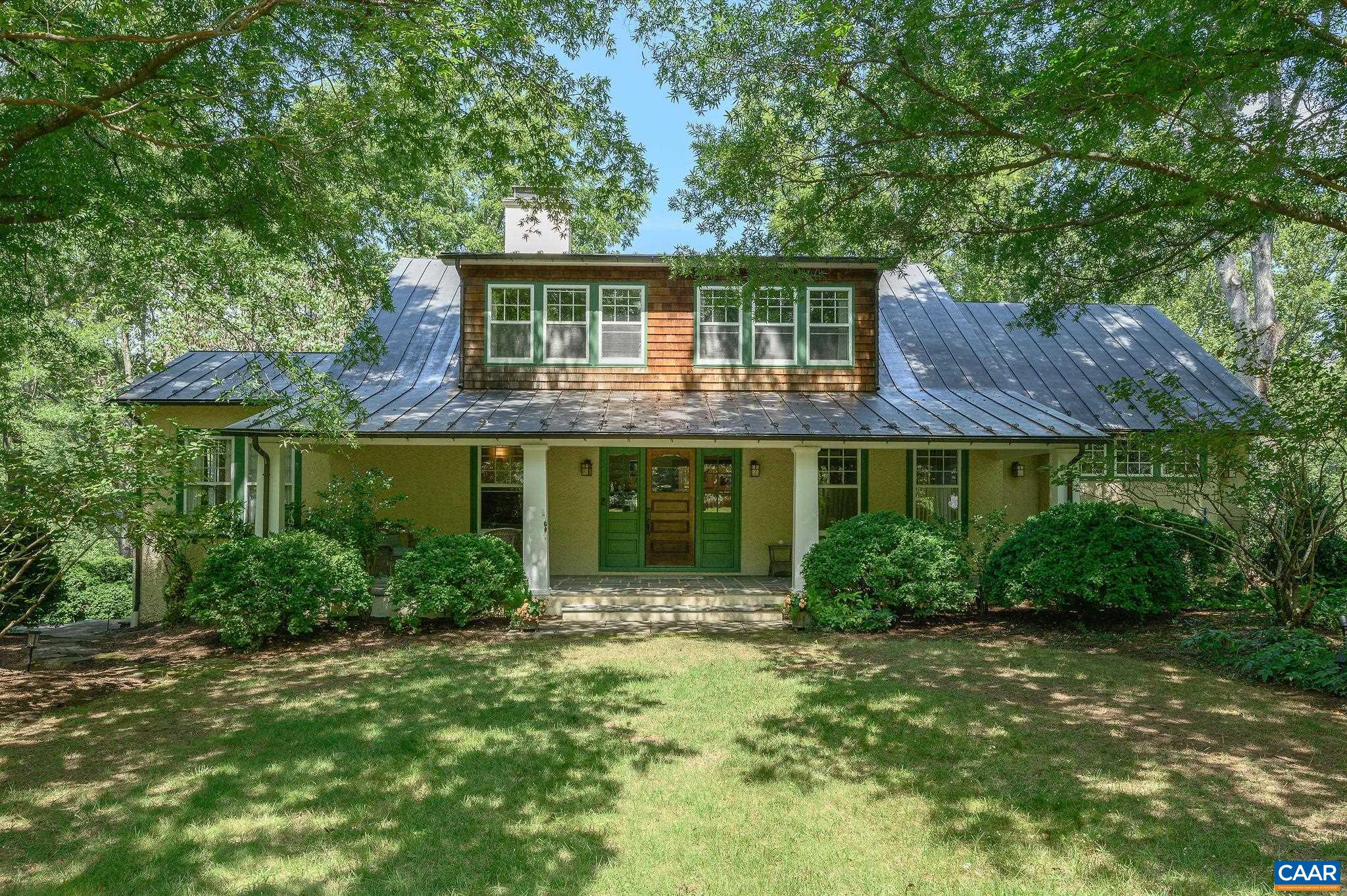 Wildwood is an exquisite example of an Arts and Craft Home maintaining the integrity of the period with 21st century improvements and additions. Built in 1917 with extensive oak woodwork defined by its emphasis on handcrafted simplicity, quality, and harmony with nature. The oak, quartersawn to highlight the straight grain, is used functionally and decoratively throughout the interior. The Built-in cabinetry highlights the joinery skills of the Arts and Crafts movement. A gracious entry opens to the living room with tile fireplace and sunlit dining room creating a flowing space. A dream kitchen and breakfast area are timeless. The Library/den has floor to ceiling bookcases and Blue Ridge Views. First Floor living is possible with the seamless addition of a first floor primary suite with private porch. The main house has 2 additional bedrooms & a 2nd floor primary bedroom, with a total of 3.5 baths. The guest house/studio has 2 full baths and versatile floorplan. The 5.6 Magical Acres have multiple porches, terraces, mahogany deck, stone walkways and walls, pool and pool house. There is a  separate Garage and Garden shed, copper roof, generator, solar panels. Only minutes to Barracks Road and town. Past Foxfield on the right.