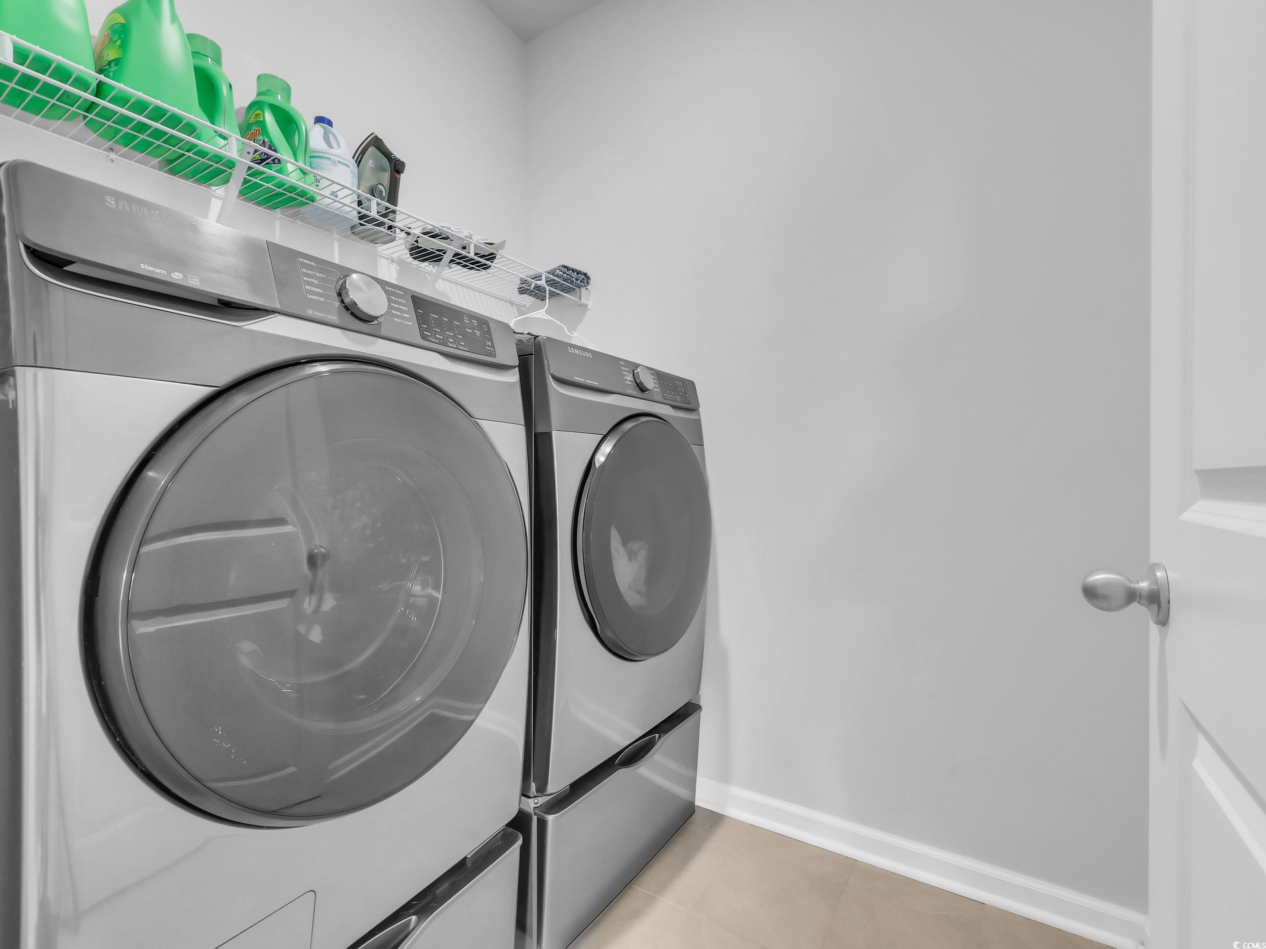 Laundry room with light tile patterned floors and washer and clothes dryer