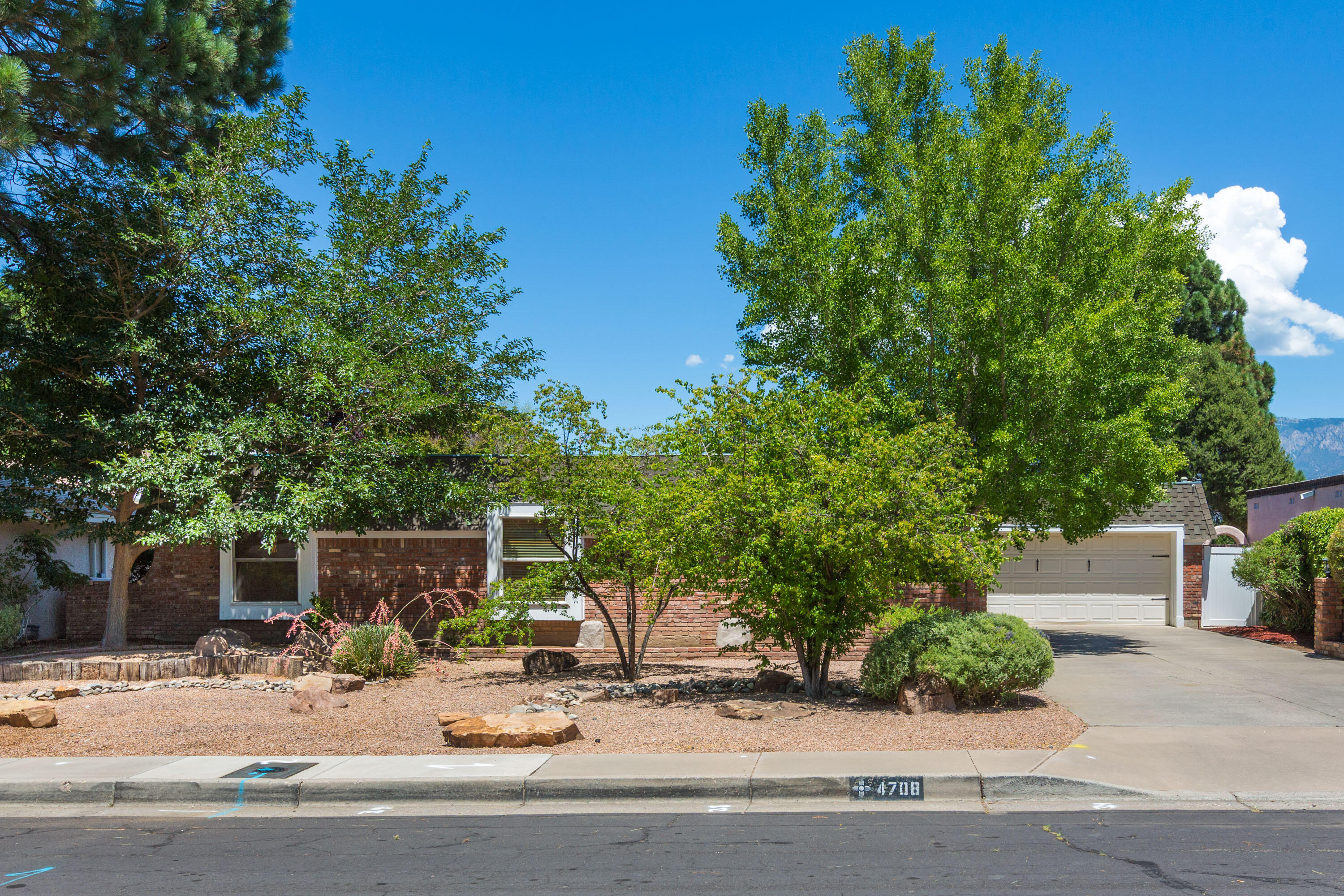 Welcome to this beautifully updated home nestled in a desirable Northeast Albuquerque neighborhood near Arroyo Del Oso Golf Course. Bursting with character, this residence offers the perfect blend of comfort, style, and functionality. Step inside to find real wood floors that flow through the living spaces. This home features multiple living areas, including one with a fireplace, ideal for gatherings/quiet evenings. You'll enjoy the AC in hot summer months! The kitchen shines with stainless steel appliances, modern cabinetry, countertops and backsplash and ample storage. Walk-in closet in the primary! Large sliding glass doors connect the indoors to the lush outdoors, where you'll enjoy mature landscaping, built in grill, a covered patio and pergola, and plenty of space for entertaining