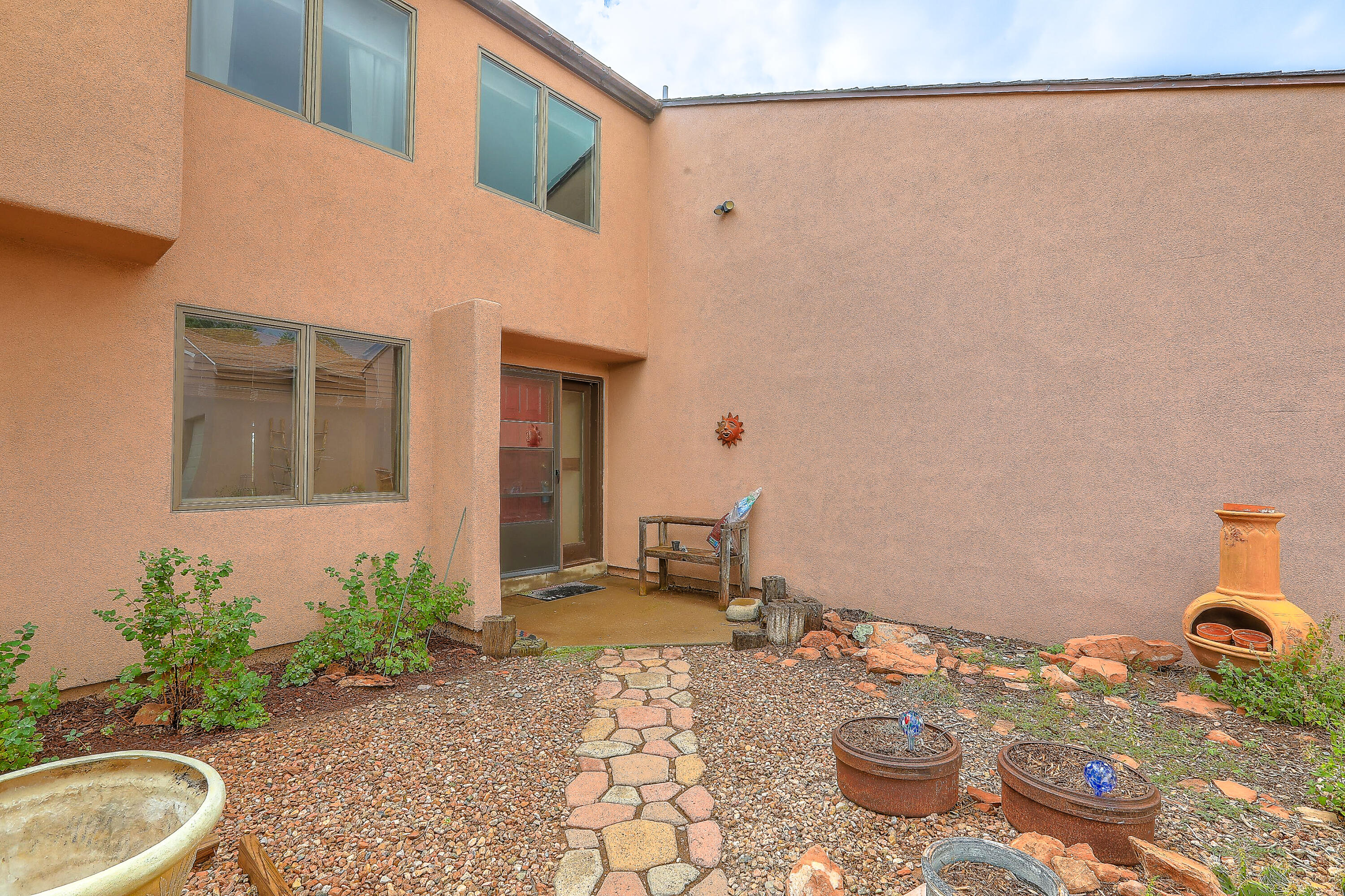 Tucked in a serene setting with incredible mountain views, this 3-bedroom home offers privacy, peace, and comfort in a gated community. Thoughtfully updated, it features remodeled baths, updated kitchen, Anderson high-altitude windows, and abundant natural light. Enjoy cozy winters with passive solar design and a recent wood-burning stove, and stay cool in summer with evaporative cooling. Outdoor living shines with a garden area, ramada, and beautifully fenced grounds. Detached two-car and one-car garages plus a workshop and storage shed provide exceptional functionality. Located minutes from the Vista Grande Community Center, hiking/biking trails, Triangle Grocery, and top-rated San Antonito STEM Elementary, this property combines country tranquility with convenience.