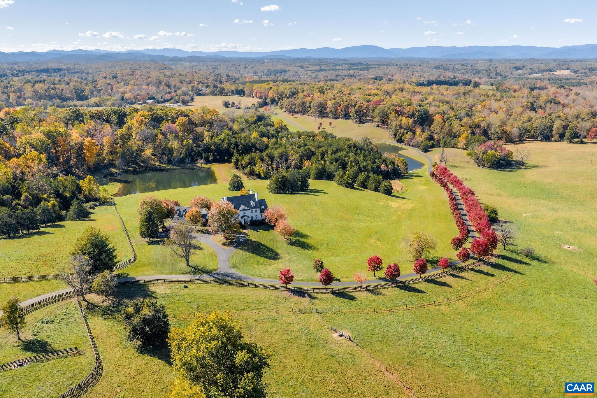 This extraordinary Georgian estate is set on 200 acres with two ponds, seven natural springs, and two barns, offering timeless elegance in a truly remarkable setting with additional subdivision and vineyard potential. Designed for both entertaining and everyday living, the home blends historic charm with modern comfort, all while capturing breathtaking mountain views from nearly every room. The main level offers a graceful mix of formal and casual spaces, including a first-floor primary suite, antique heart pine floors, and a handsome study. Upstairs, a second primary suite with a renovated bath enjoys panoramic vistas, complemented by three additional bedrooms with en-suite baths. The lower level is designed for recreation with a large screen viewing area, wet bar, billiards room and provides a welcoming guest bedroom, full bath and office. Seven fireplaces add warmth and character. Outdoor living boasts a free-form pool, wide porches, and sweeping vistas. A four-car garage with portico has a second floor roughed-in. Every detail reflects quality and sophistication, making this estate a rare opportunity where land, luxury, and lifestyle come together, and every feature is designed to elevate gracious country living.