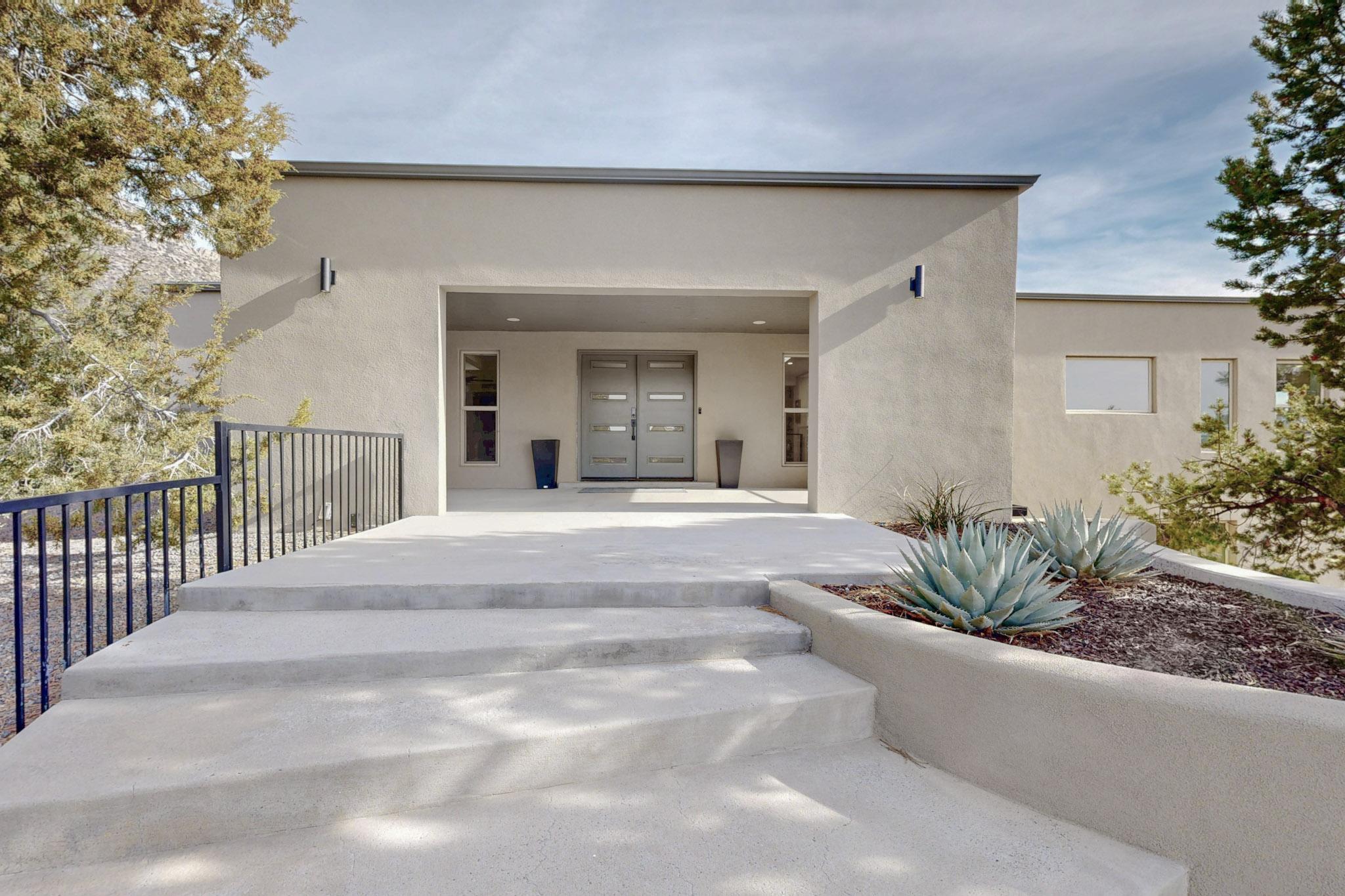 Nestled in the foothills of the Sandia Mountains and minutes from the Tram and trails, sits this comprehensively remodeled 7,700+ sq/ft, 5 bedroom, 7 bathroom home with BOTH city and mountain views. The unique nature of this lot gives you seclusion and privacy. With a warm-modern aesthetic you'll feel right at home. The kitchen features counters and walls clad in Dekton. With 2 Primary Suites at opposite ends of the home, privacy is easily achieved. Both primary suites have spa-like en-suites with 2-person soaking tubs, heated floors and custom tile. The backyard features covered patios, deck, putting green and pergola. The heated pool has an automatic cover, jacuzzi and Baja shelf. Multi-zone refrigerated air and solar.