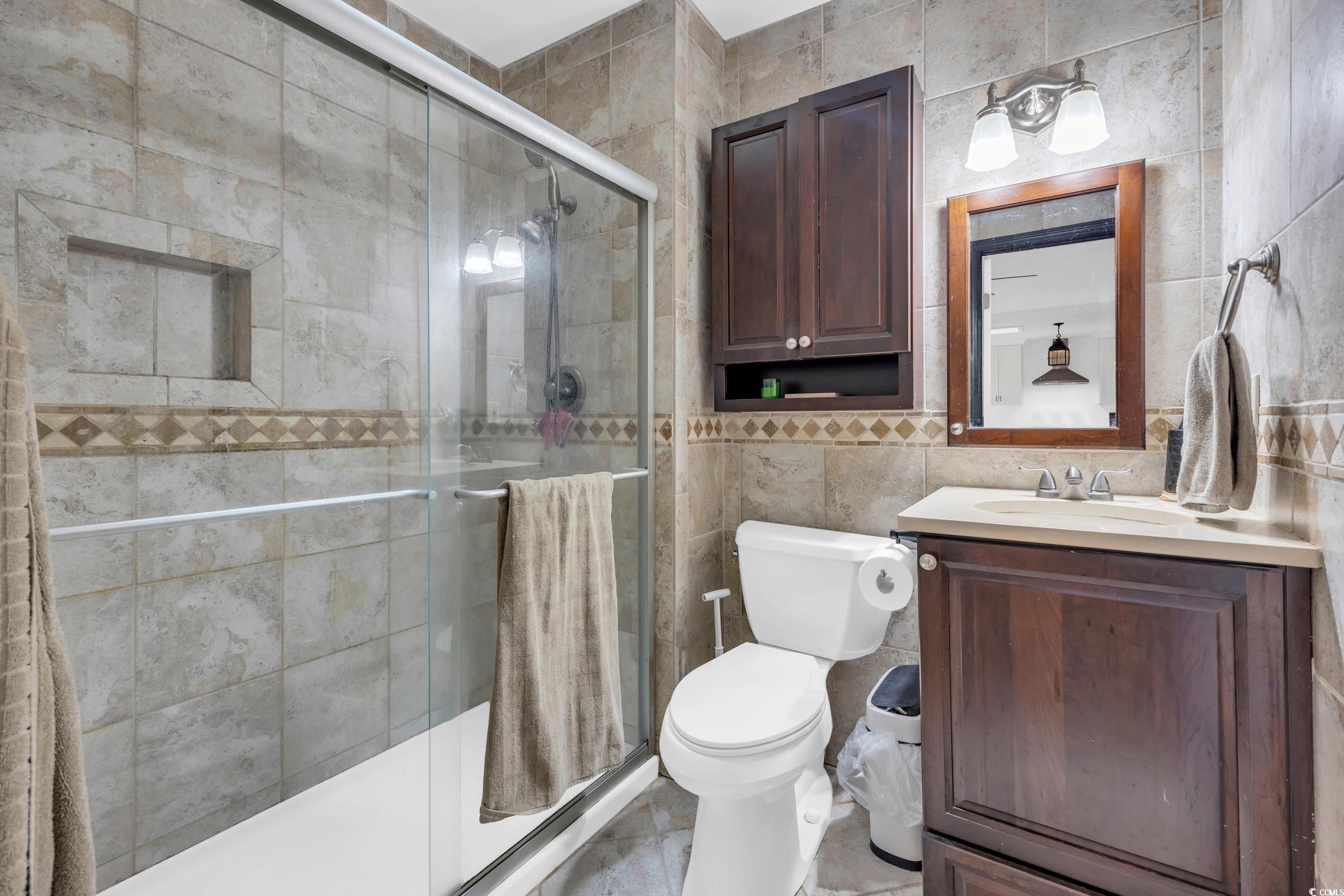 Full bathroom featuring tile walls, vanity, a shower stall, and tile patterned floors