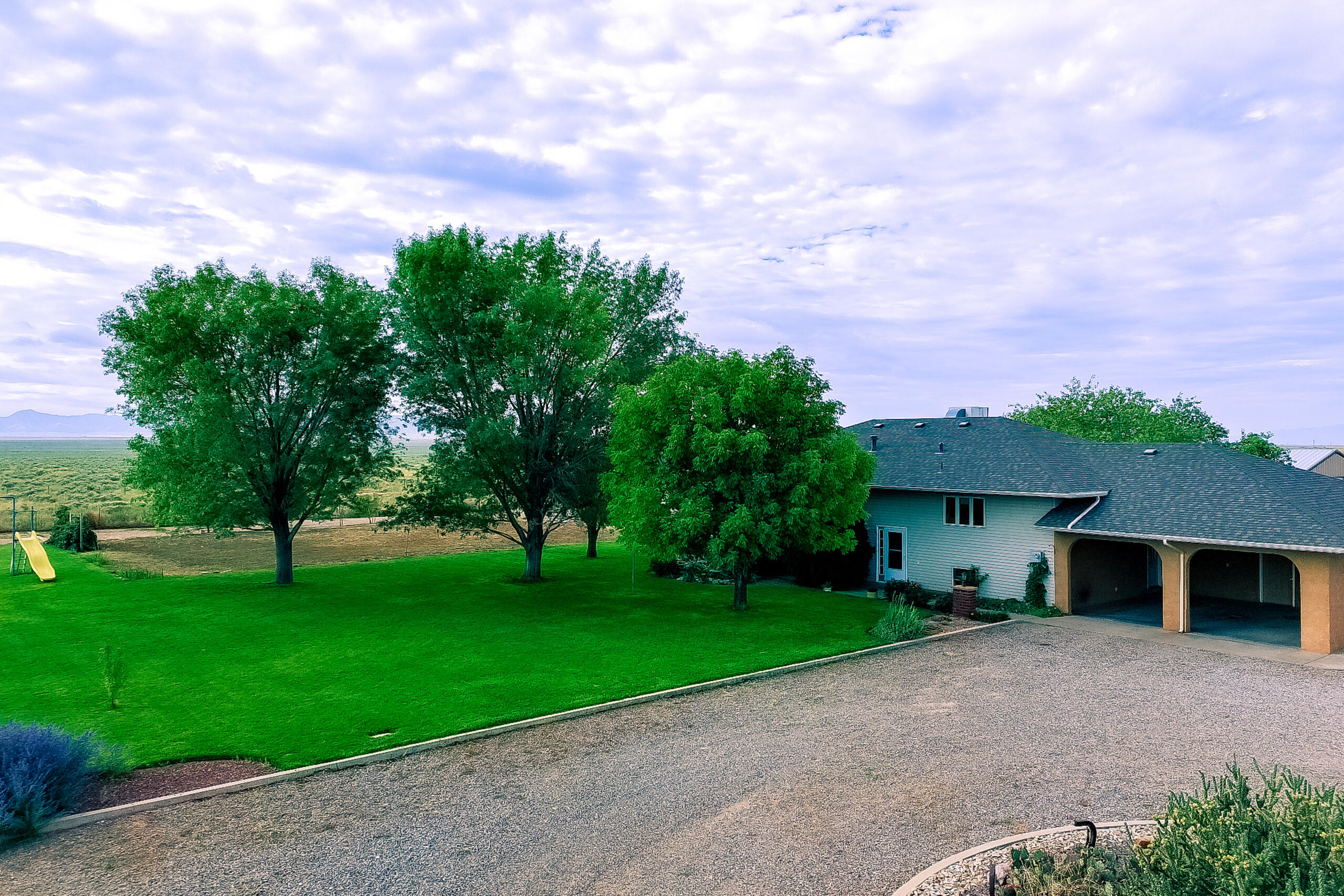 5-acre split-level property with residence, workshop, and agricultural improvements.Upstairs includes a kitchen with vinyl flooring, food prep area, walk-in pantry, oak cabinetry, and large dining area. Spacious family room with large windows w/mountain views, primary bedroom w/ full bath, secondary bedroom, & large laundry w/wash sink, office space & additional full bath. Downstairs includes 2nd kitchen, dining area, three bedrooms, full bath w/ dbl sinks & tub/shower combo, second living area & storage room. Amenities include  central vacuum system, Pella thermal double-pane casement wood windows, hot water baseboard radiant heat w/ four zones, & MasterCool evap AC. Roof is pitched asphalt shingle; exterior is vinyl siding w/stucco accents.