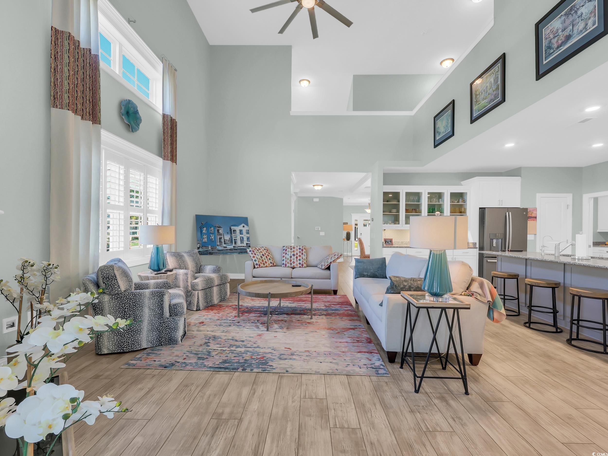 Living room with a high ceiling, light wood-style floors, and ceiling fan