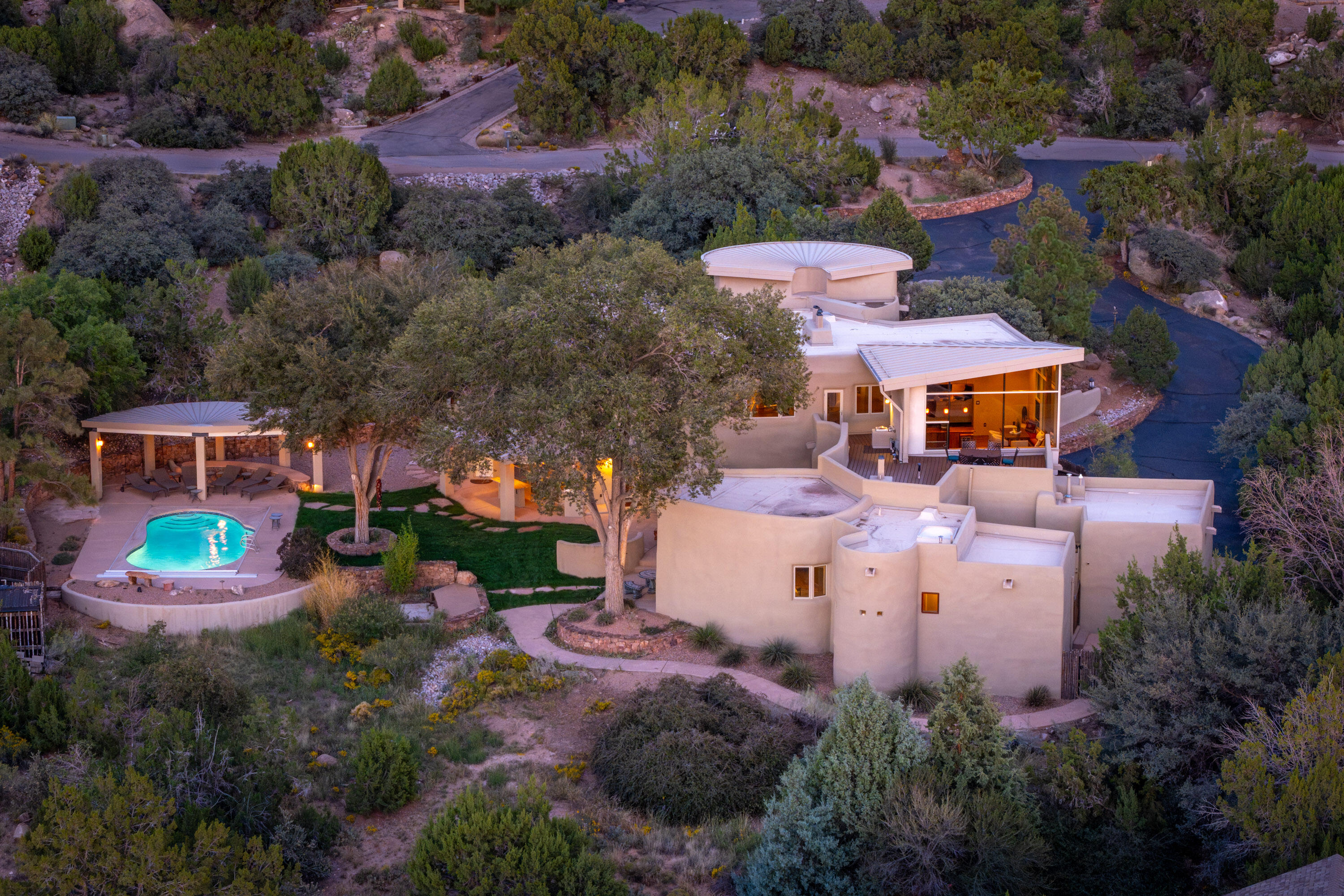 Perched high in Sandia Heights, this extraordinary home captures breathtaking views of the Sandia Mountains by day and the twinkling city lights of Albuquerque by night. Thoughtfully designed with artistic flair, the residence showcases curved adobe walls, expansive windows that bathe the interior in natural light, and exquisite handcrafted details throughout. From hand-scraped hardwood floors and reclaimed architectural elements to custom tilework, furniture-grade cabinetry, and rich granite surfaces, every finish speaks to timeless craftsmanship. Designed for effortless entertaining, the home offers a seamless indoor-outdoor flow with an outdoor kitchen, lushly landscaped grounds, and a sparkling in-ground pool--all framed by unmatched views. A rare opportunity to own a work of art!
