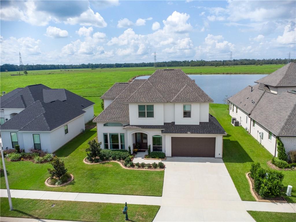 MOTIVATED SELLER! This stunning 3 year-old custom-built home, located in the beautiful Ashton Plantation subdivision, is ready for you to call "home." Boasting 4 bedrooms, 2.5 baths, & an office. The living area is a showstopper with 12-foot ceilings, crown molding throughout, and a wall of windows that showcase breathtaking lake views while flooding the space with natural light. Great for entertaining, features a large gas fireplace, custom shelving on both sides, w/room for an 85-inch TV. Vinyl plank flooring flows throughout the home. The gourmet kitchen is a chef's dream, equipped with large island topped w/stunning Quartzite, SS appliances, double ovens, a 5-burner gas stove, & soft-close cabinets. The primary suite feels like a retreat, offering serene lake views and a luxurious en-suite bath. The vanity is impressive with its Quartzite top, stand up shower, soaking tub & spacious walk-in closet. Downstairs, you'll also find a large laundry room w/sink & Quartzite folding table, a 10x4.5 butler’s pantry or lrge storage closet, an office, 1/2 bath, & a cozy sitting room, great for reading/gaming. Upstairs includes 3 additional bedrooms, a full bath w/soaking tub, marbled walls and a separate sit-down vanity. The 20x16 bedrm can double as a recreation room. Storage is plentiful w/2 walk-in attic spaces equipped w/shelving. Step outside to enjoy the serene views from your covered back porch. Beyond the lake, no further development, ensuring your peaceful surroundings remain undisturbed. Additional features include a 2-car garage with 11x7 work area w/shelving, outdoor soffit lighting in front, tankless water heater, front garden sprinkler sys, security cameras, speakers in living, primary, garage, & outdoor patio. Located in St.Charles Parish, just 12 minutes from Metairie, subdivision offers family-friendly amenities, including walking path, play area, & community pool.
