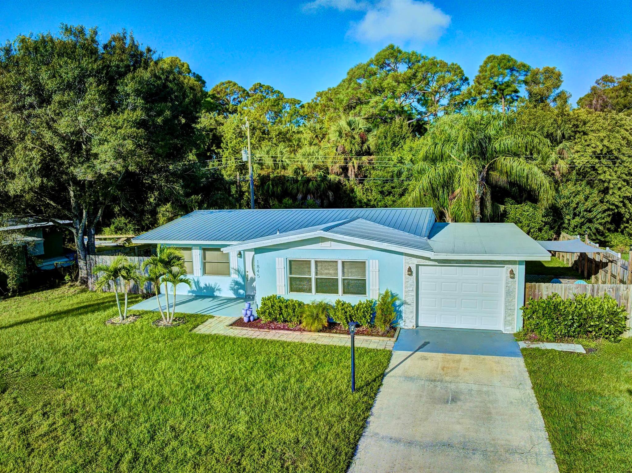 BEAUTIFULLY UPDATED VINTAGE GEM! 3BR/2BA CBS home w/1Car Gar tucked in a quiet neighborhood. UPGRADES: 2025 HVAC, 2024 METAL ROOF! 2022 remodeled GOURMET EAT-IN KITCHEN  w/2025 GE wall oven, 2019 SS Whirlpool appl's, island cooktop, soft-close cabs, pot & specialty drawers, granite C/Ts, & recessed lighting. Light-filled, open-concept living areas feature gray plank tile floors. LuxVinyl floors in all bedrms. Stylish remodeled full bathrm. A/C'd laundry and storage rms. OUTDOOR: Shaded pavered patio, fire pit, a fenced backyard w/mango, banana & starfruit trees backing to peaceful woods. Double-gate entry for toys. NO HOA! LOC: Mins to shopping malls, golf, tennis, cafes, restaurants, theaters & medical.  Small-town charm, coastal lifestyle--EAT, PLAY, LIVE VERO BEACH!