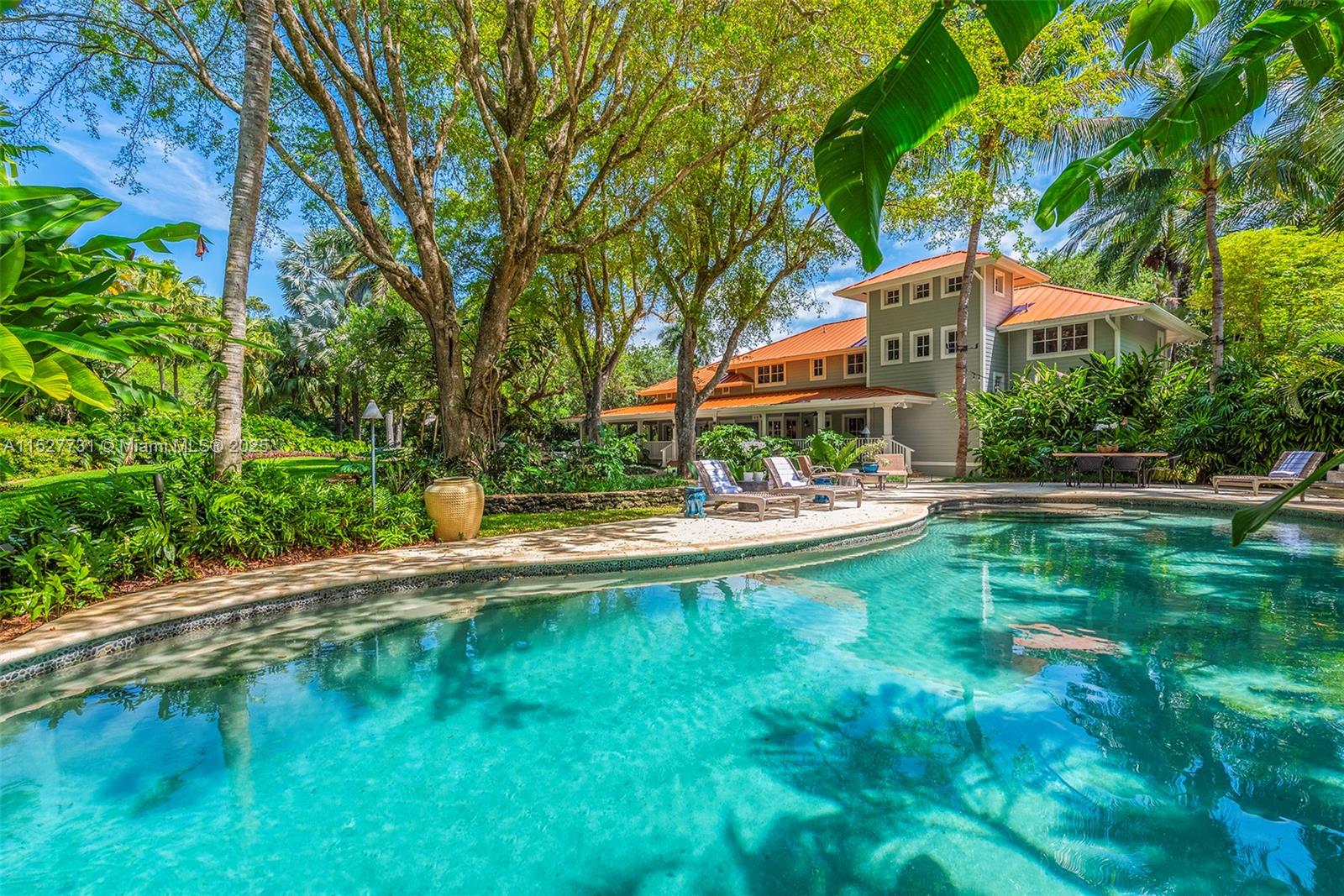 Located in the guard-gated Banyan Lakes neighborhood, this 2003 custom Old Florida estate-style home w/ wraparound porches spans 8,765 SF & is the epitome of sophisticated living.  Situated on a 50,000+ sf lot that is nothing short of magical w/ live oaks, terraced lawn, & lush landscaping around the lagoon-style pool & patio. The 6 BR, 5.2 BA home w/ floorplan that calls for entertaining features a formal liv rm that opens to a zen garden & family rm w/ custom built-ins & fireplace. The bespoke kitchen incl Caesarstone counters, Wolfe & Subzero appliances, banquette & butlers pantry.  The primary ste has  large BR, gym, 2 walk-ins, & spa-like BA. There are 4 add’l BRs upstairs + office. White oak floors, impact glass, 2014 metal roof, generator, 2-car gar are some of the special features.