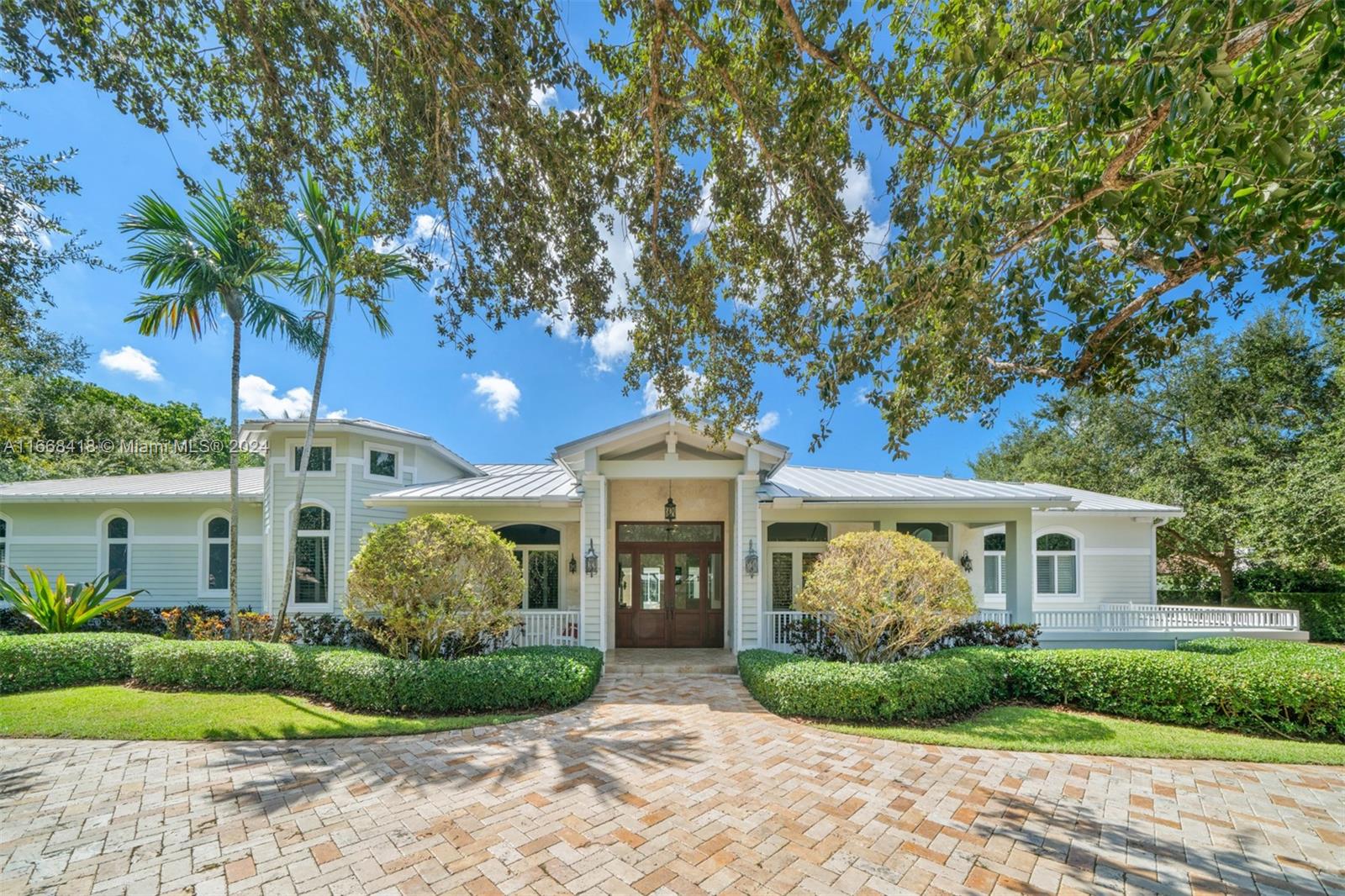 This tropical, 1-story gated estate, with its contemporary metal roof, is expertly crafted to offer the perfect blend of relaxation and entertainment. Step into an open layout where the kitchen seamlessly flows into the formal dining room and spacious living area, featuring an impressive grand bar perfect for hosting. The secluded primary suite offers privacy on the opposite side of the house, with a luxurious bathroom that includes separate sinks, a soaking tub, and a separate shower. Step outside to a vast 38,768 SqFt lot featuring a covered terrace, BBQ area, and inviting seating perfect for outdoor gatherings. The property also includes a basketball court surrounded by lush greenery, offering an ideal space for both relaxation and recreation.