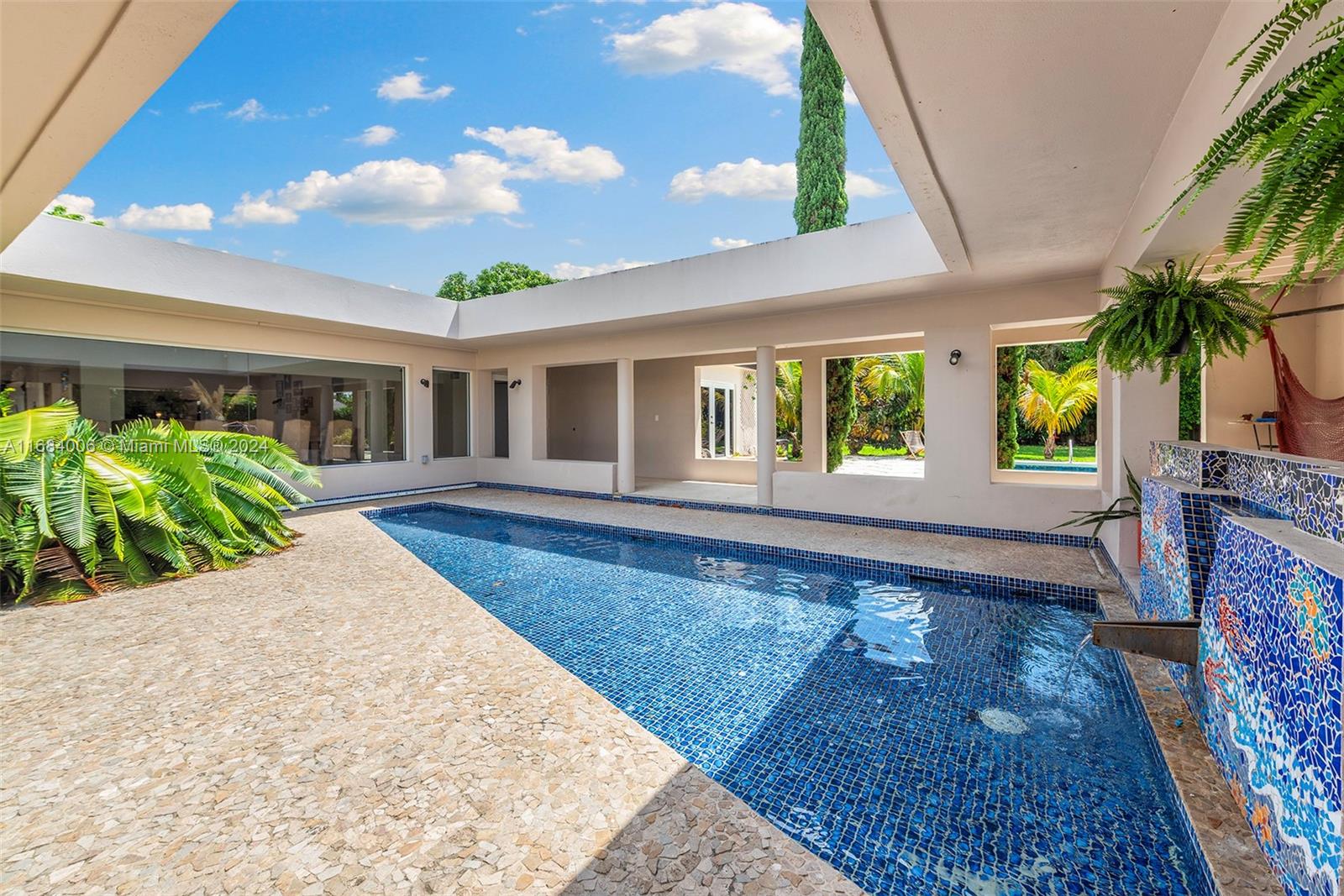 Discover luxury living at its finest in this meticulously renovated Mid-century modern masterpiece. Designed by world-renowned architect Kenneth Treister, this home wraps a tropical atrium with stunning walls of glass, original mosaic & water sculptures, stained glass grand entry all beaming in natural light. This estate home boasts 6 bedrooms + den, 6 baths with over 5200 SF of living space on a sprawling 33,000 SF lot. High-end finishes throughout, brand new chef's kitchen with state-of-the-art appliances, impact glass & spacious 2-car garage. Incredible outdoor living & entertaining spaces, outdoor fireplace & tropical sparking pool create the ultimate in Florida living. Nestled in the prestigious Village of Pinecrest, this is a rare opportunity to own a truly one-of-a-kind Miami gem.