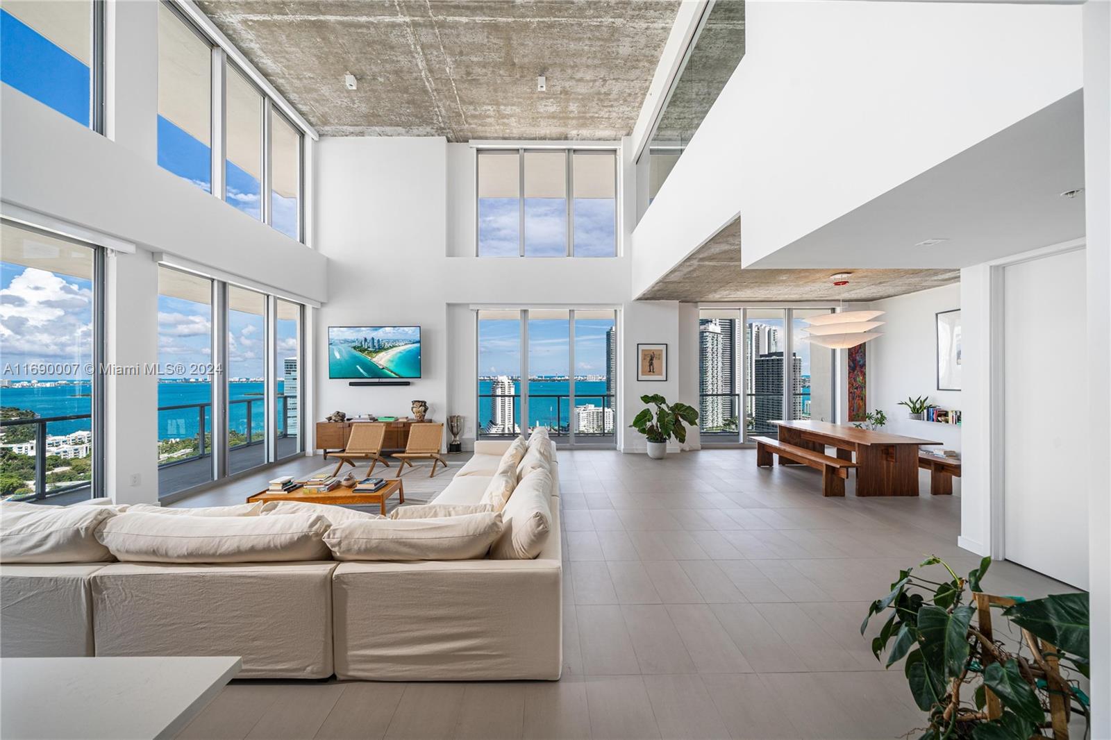 Experience the epitome of Miami luxury living in this fully renovated corner duplex penthouse with double-height ceilings, offering expansive bay, ocean, and city views to the north and east. This two-story residence at 2Midtown features wrap-around balconies on both floors, providing over 1,300 Sqft of outdoor living space with panoramic vistas. The interior boasts 3,193 Sqft of living space, including 3 beds plus a den and 3.5 baths with luxury touches throughout. The well-appointed kitchen is equipped with Miele and Gaggenau appliances, Waterworks fixtures, and cabinets fashioned in a tasteful walnut veneer, complemented by an Adamina Quartz countertop. The Porcelain flooring has a Sound Control/Proofing System, and all windows and glass panels are outfitted with motorized blinds.