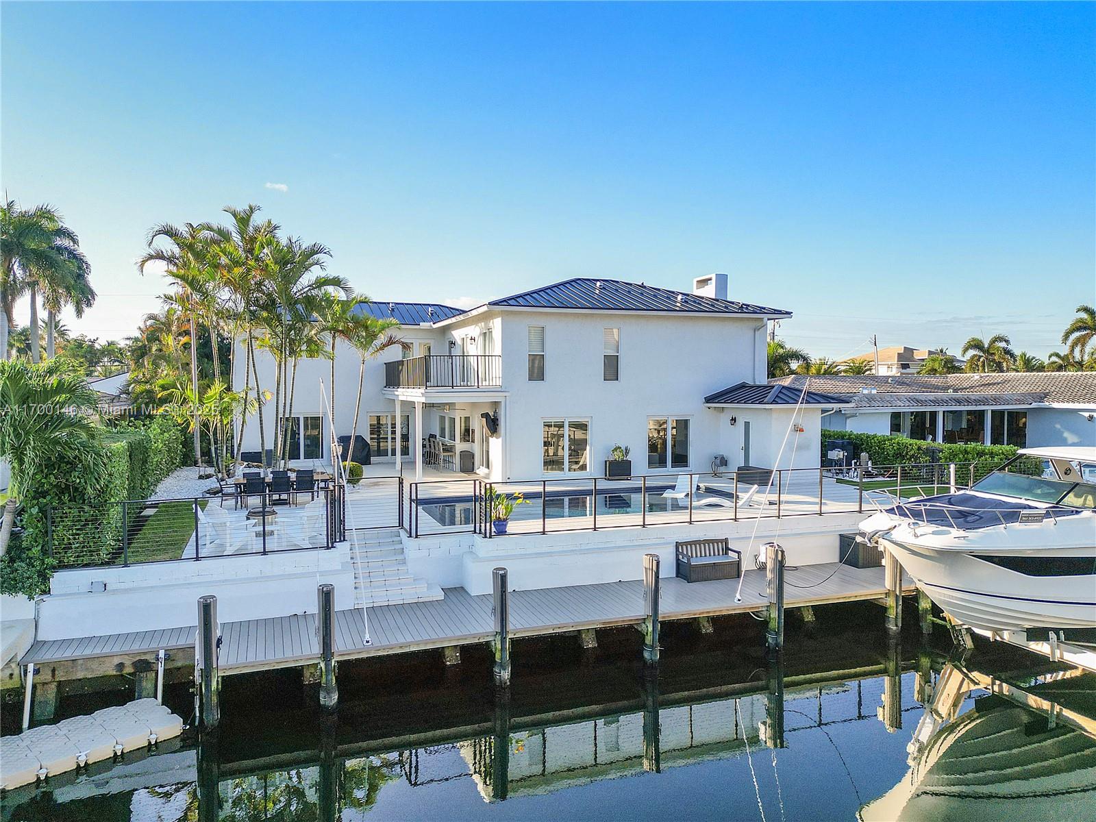 Discover this beautifully remodeled home featuring three en-suite bedrooms, a large versatile den, and an additional bathroom, situated on an exclusive island street, just minutes from Hillsboro and Boca inlets with no fixed bridges. Boating enthusiasts will appreciate the 80 foot composite dock equipped with two 30/50 amp power pedestals and a 20,000 lb. boat lift. This stunning property offers a newer metal roof, high impact windows, updated landscape, a completely renovated pool and patio area, remote blinds, an updated serene 700 gallon Koi pond, a whole house generator, new turf, completely redone veranda on second floor and new surround sound . The chef's kitchen with seamless oversized quartzite Island with storage, top of the line appliances and custom flip out windows.