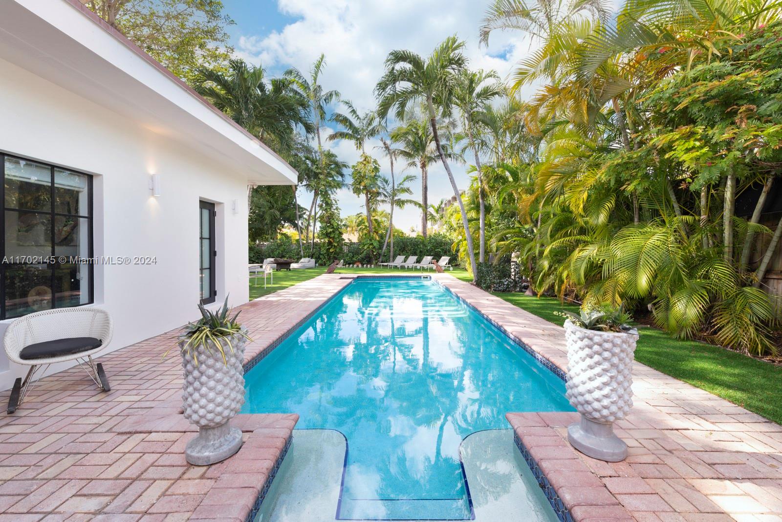 Built by renown architect, Carlos Schoeppl, this 1930’s Deco-era Miami Beach “swimmers paradise” features an oversized 42-foot-long saltwater pool, which is a-blaze during the awe-inspiring sunsetting afternoons. The one-story residence flows naturally from the expansive vaulted ceiling as you enter the cheerful light-filled space & reveals an open floor plan boasting designer built-ins for elegant decorative & storage needs. The privacy orientated layout features 3 on suite bedrooms, with the primary suite opening directly onto the pool. A fourth room is a perfectly located space with versatility to make a lovely fourth bedroom, a gym/nursery/meditation, or office space. Special architectural details, such as the built-ins and Emtek, “SPOKE” interior door hardware and new solid core doors