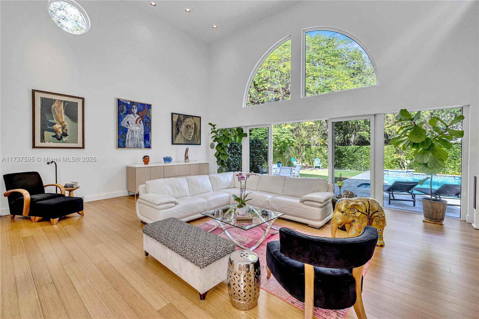 Step into this spacious living room with soaring 20-foot ceilings and wall-to-wall impact glass windows that open to a private, gated yard, shaded by the canopy of a majestic royal poinciana. A tranquil pool with waterfall adds to the serenity. This unique 2-story, 3-bed, 2.5-bath contemporary corner home blends generous natural light through its unique glass windows and skylights with exceptional privacy. Updated with high-end finishes including bamboo flooring throughout, fully remodeled chef’s kitchen with premium appliances and updated, modern bathrooms. Outdoors enjoy beautifully landscaped grounds with elegant lighting and an inviting newer granite deck for al fresco dining and entertaining.  Full 2-car garage. No flood zone. Walk to top schools, restaurants & shops in the Grove.