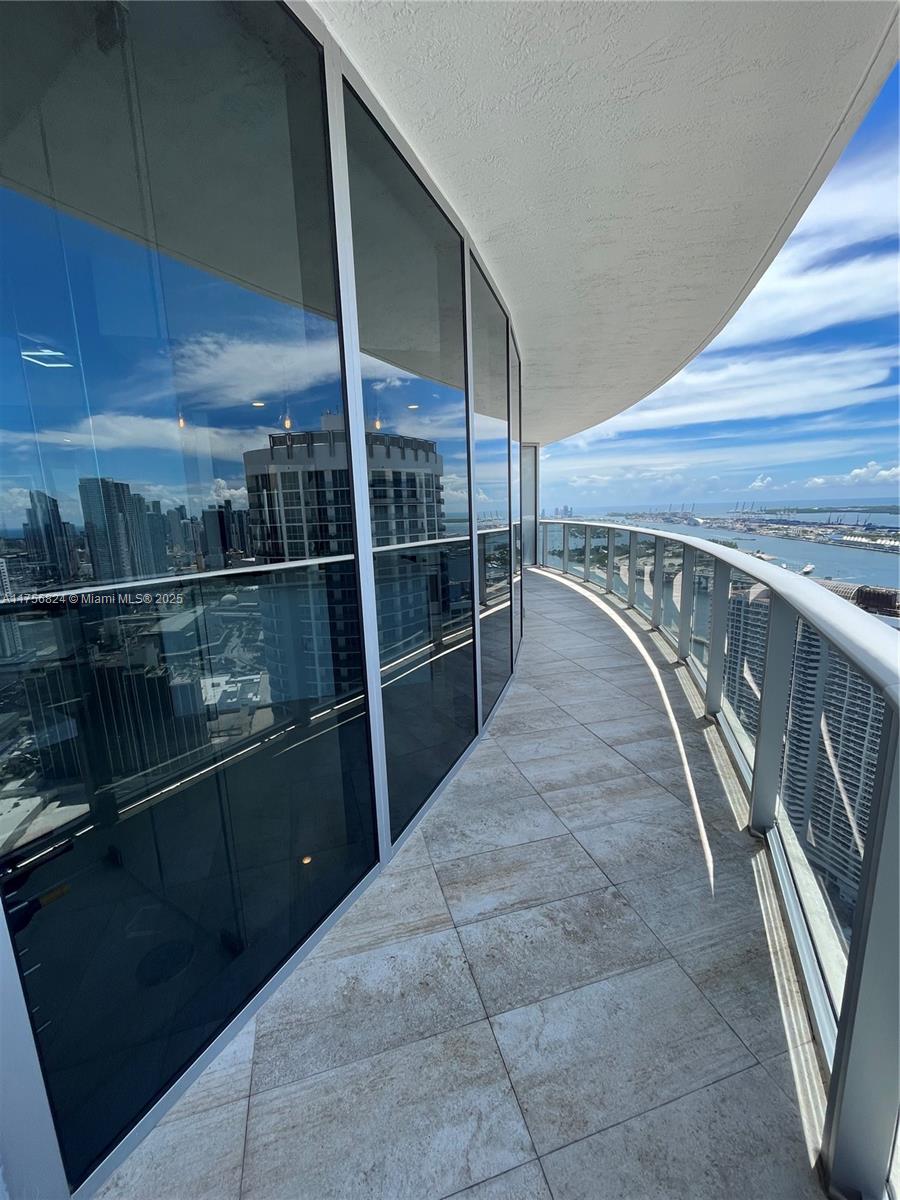 Experience refined living in this elegant corner unit at Aria on the Bay. Unit 5000 is located in one of Edgewater’s most prestigious towers, featuring an open layout with sleek porcelain floors and floor-to-ceiling impact windows. The wrap-around balcony offers expansive views of Biscayne Bay, the Miami skyline, and sunsets.

Modern geometric lighting enhances the space, while the open living area connects seamlessly to a well-appointed kitchen. Steps from Margaret Pace Park and minutes from Miami World Center and the Design District.

Residents enjoy top-tier amenities, including pools, a fitness center, spa, and lounge. A rare opportunity to own a high-floor residence in a prime Miami location.