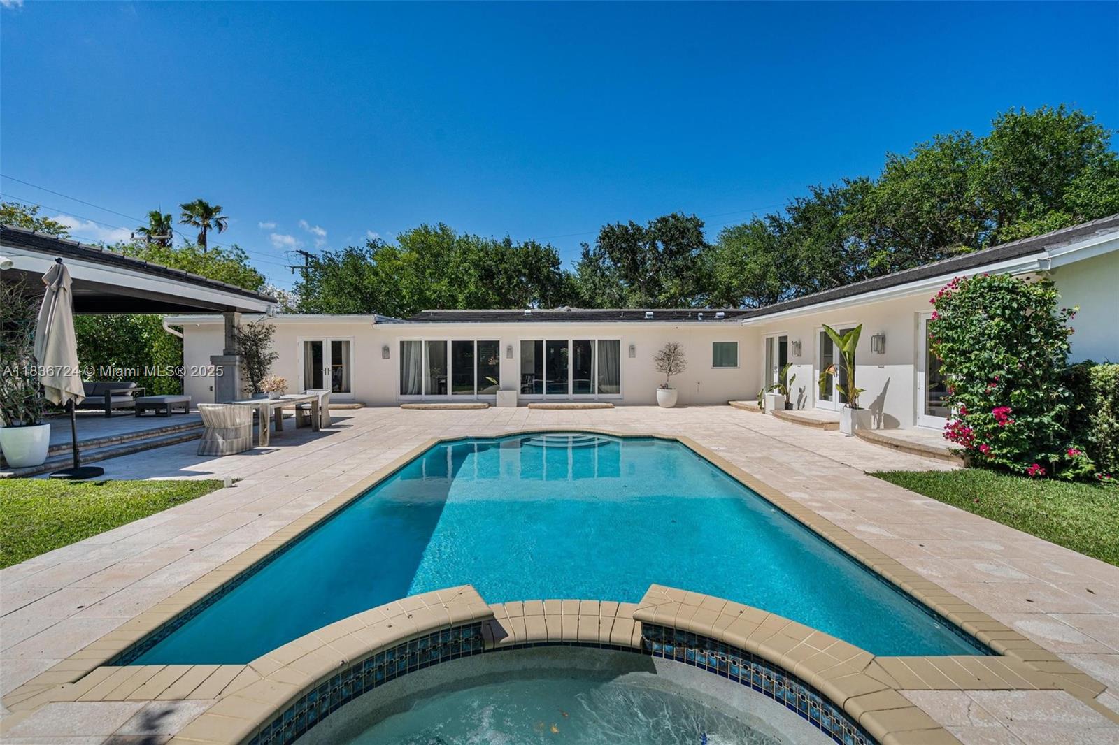 A pristine and elegant Pinecrest residence, set behind a graceful circular driveway and secure electric gate. Offering 4 bedrooms and 3 bathrooms across 3,152 sq ft, this home is designed for both comfort and ease. The sunlit primary suite includes a generous walk-in closet. A bright kitchen features stone countertops, plentiful cabinetry, and a cozy breakfast nook. The open dining area with built-in bar invites entertaining. A  spacious office or family room offers versatility. Outside, enjoy a large covered summer kitchen with built-in BBQ, lounge space, saltwater pool, and spa—ideal for enjoying the South Florida lifestyle. Surrounded by oak trees and lush tropical landscaping, this property offers a private, serene oasis close to everyday conveniences including Pinecrest schools.