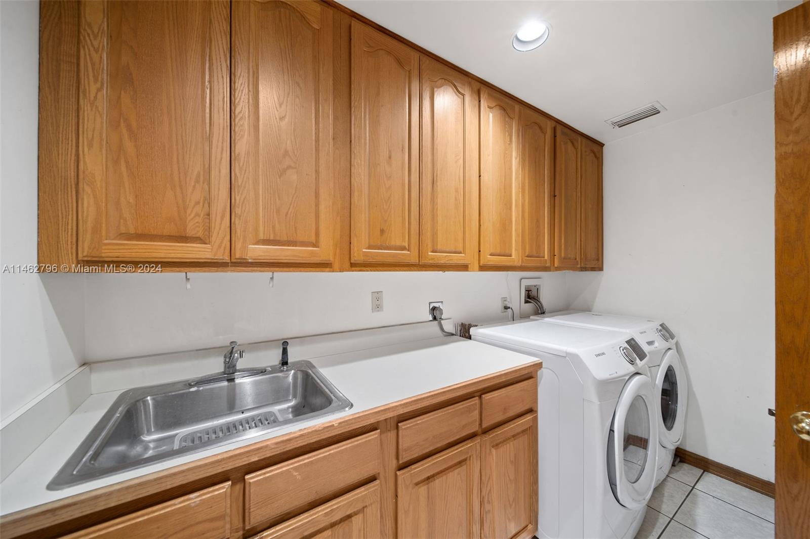 Large laundry room with folding area, sink, and storage cabinets